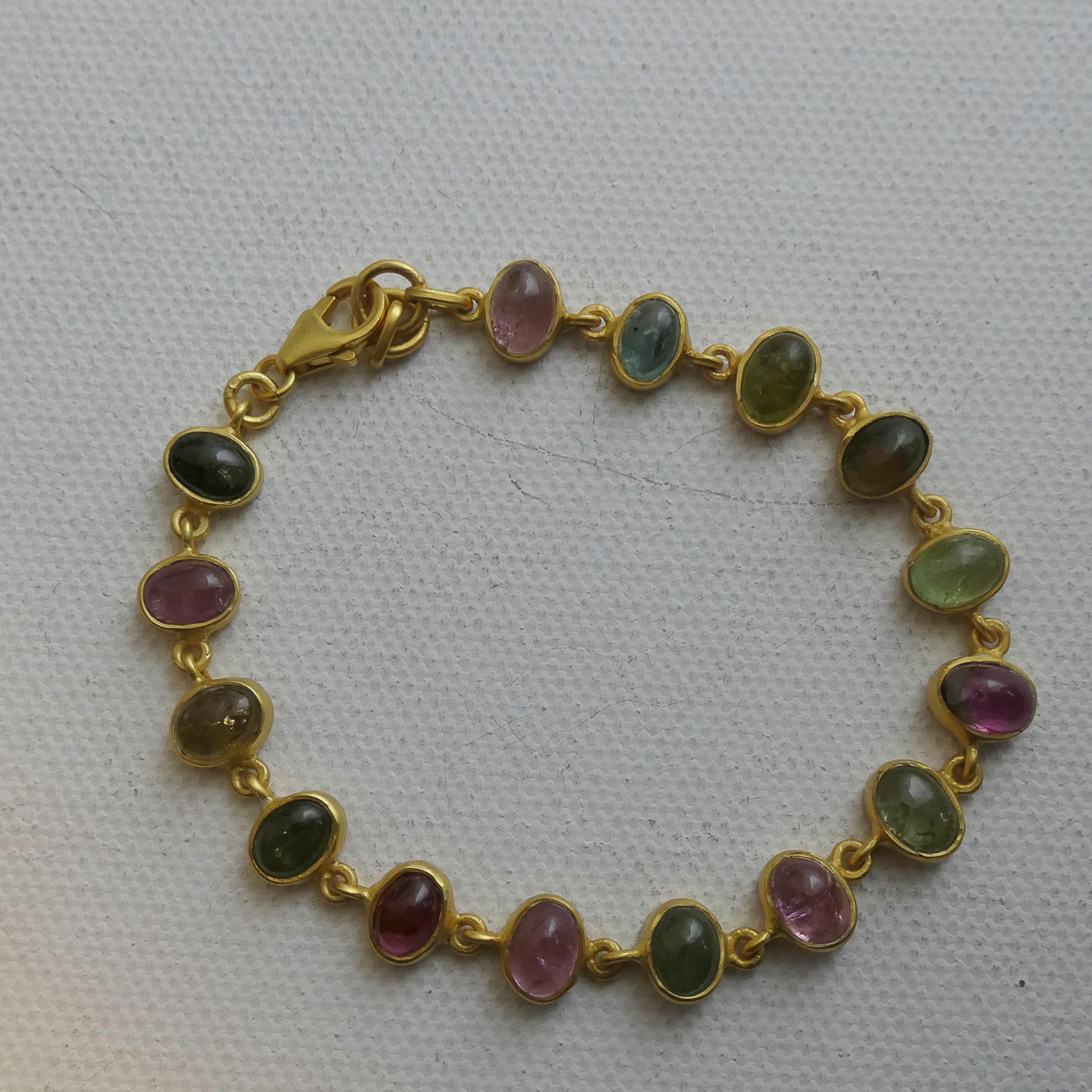 Add a vibrant touch of elegance to your jewelry collection with this exquisite bracelet featuring a series of 4x6 mm cabochon-cut natural tourmalines. Each gemstone is uniquely colored—ranging from soft pinks and greens to warm golden and deep