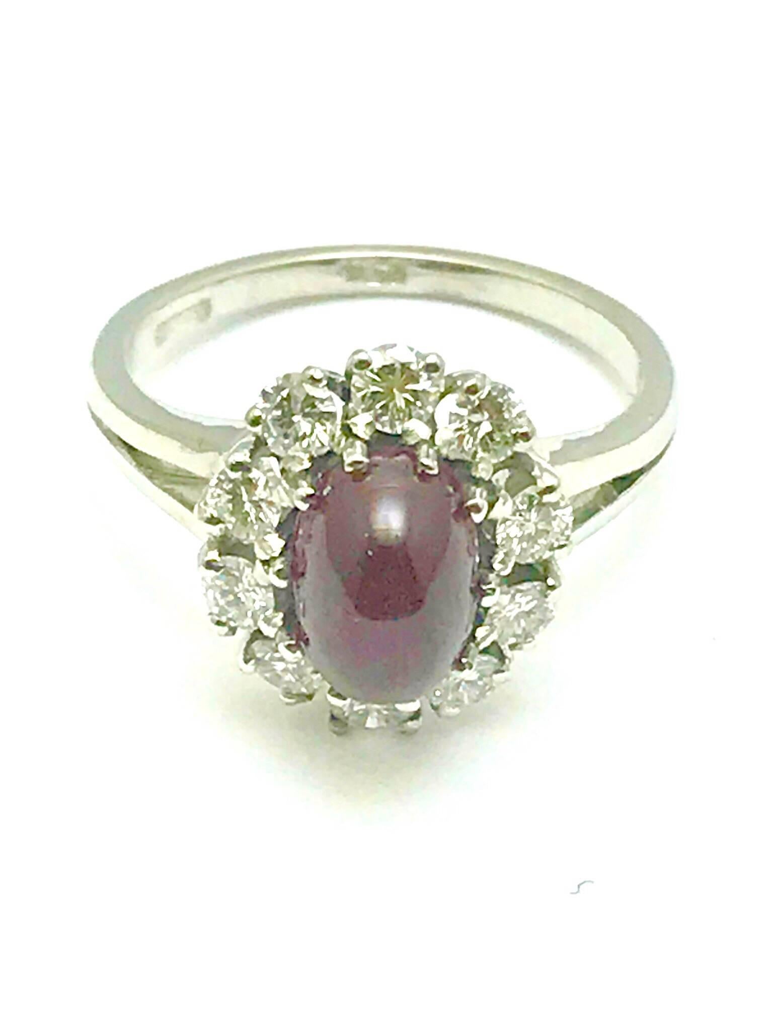 A cabochon natural ruby and round brilliant diamond 18 karat white gold ring.  The ruby is 2.46 carats, prong set, with ten diamonds surrounding it.  The diamonds have a total carat weight of 0.70 carats, and are graded as G color, VS clarity.  The
