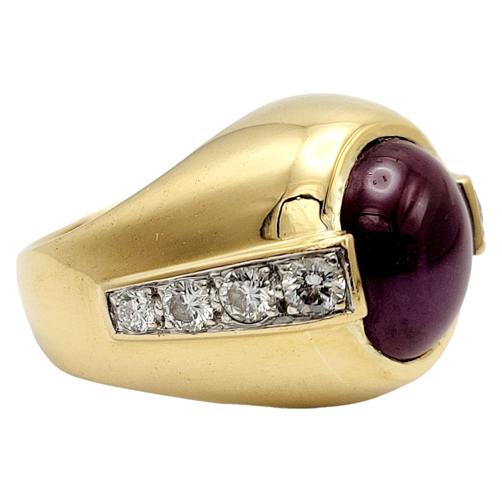 Ring Size: 8.5 

This exquisite 18-karat yellow gold dome ring boasts a captivating 8.87-carat natural ruby cabochon and 0.72-carat round brilliant cut diamond accents.
The focal point of this ring is a stunning natural red ruby cabochon, cut to