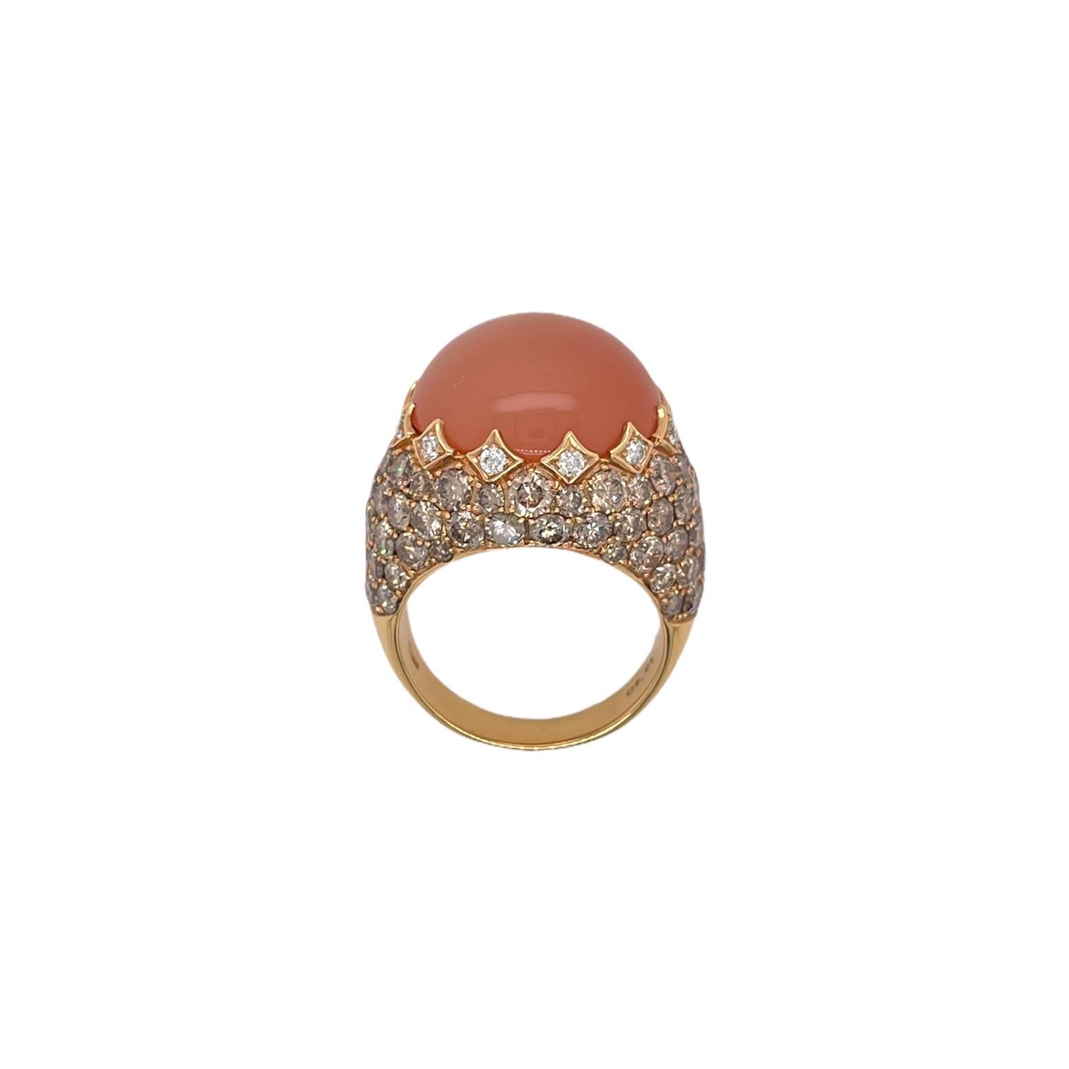 Elegant orange moonstone and champagne diamond cocktail ring in 18k yellow gold. Ring contains 1 round cabochon cut orange moonstone, 17.61ct. Center stone is accented by champagne diamonds, 5.76tcw and white round brilliant diamonds, 0.25tcw. Ring