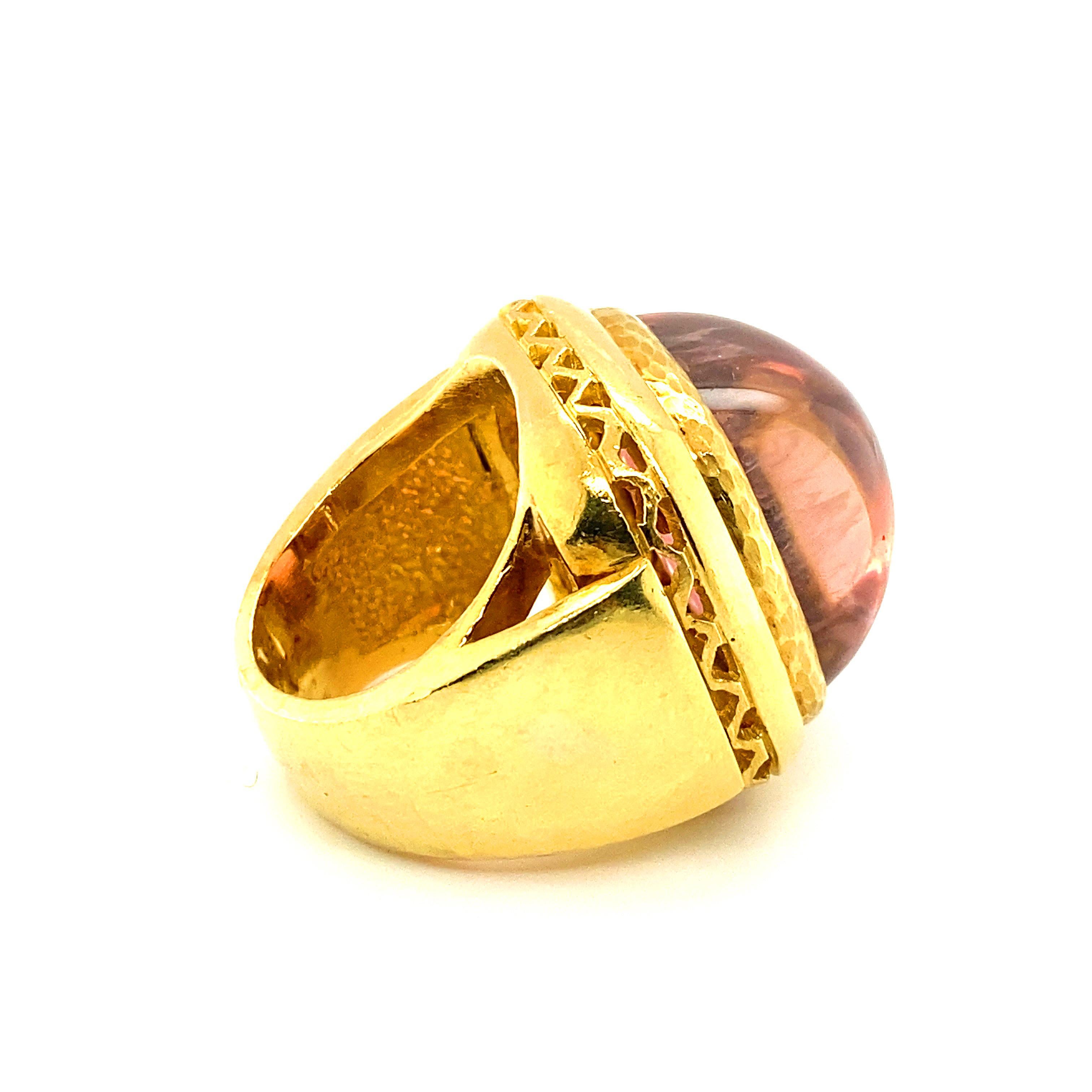 A cocktail ring designed around a brilliant cabochon pink tourmaline of approximately 34cts.  The stone displays a deep, brilliant pink when viewed straight on, and picks up a peach undertone when viewed from the side.  The stone has a pinker hue