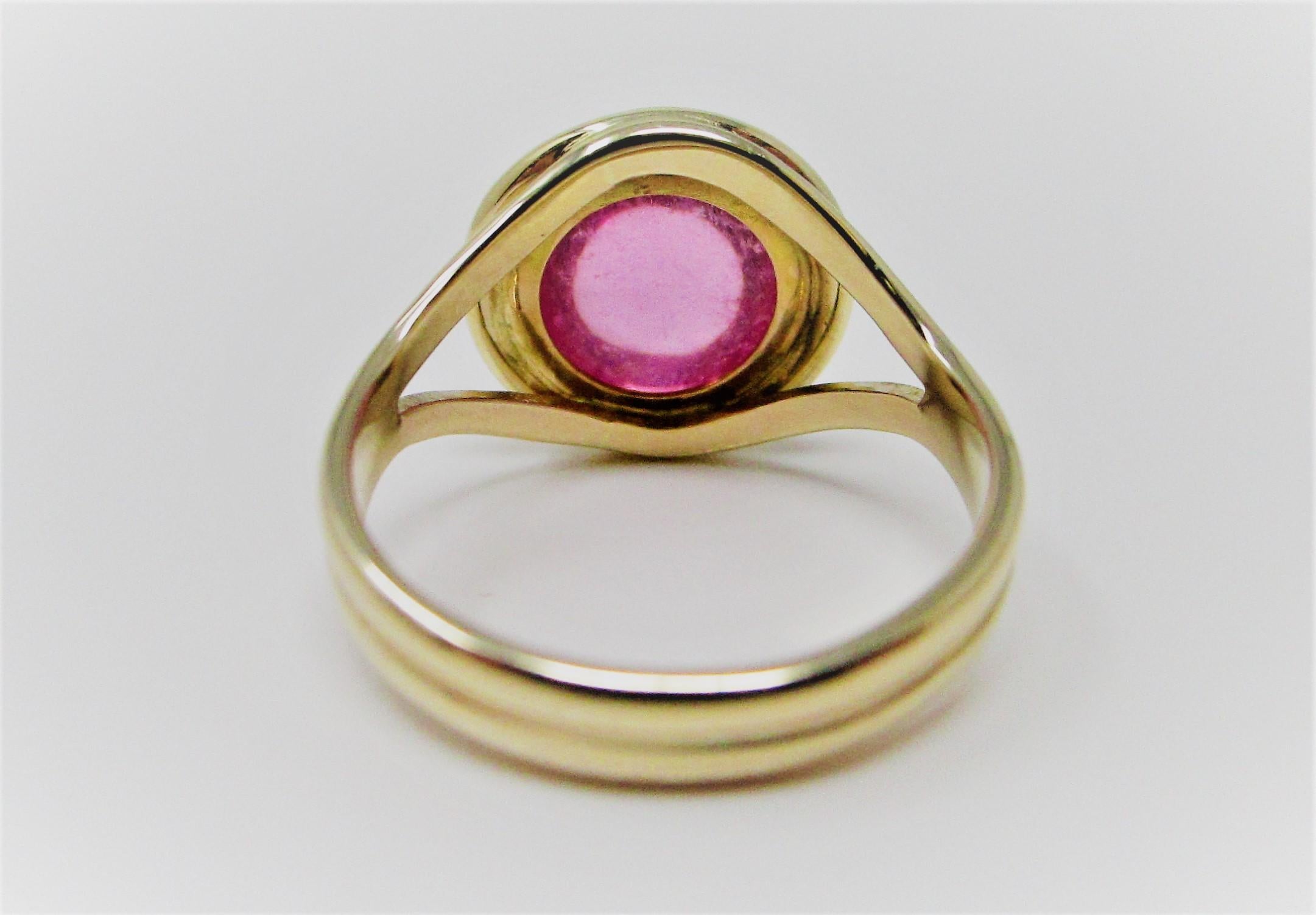 Bezel set cabochon pink tourmaline ring in 14 karat yellow gold.  This is a great modern piece with a designer look!  Size 7.
