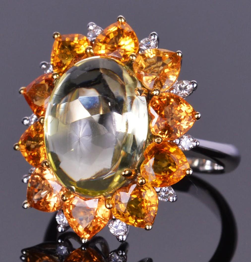 This ring truly is a showstopper! With a beautiful 9.43 carat cabochon quartz set with halo filled with 6.45 carats of stunning orange sapphires and .25 carats of diamonds in 14k white gold.