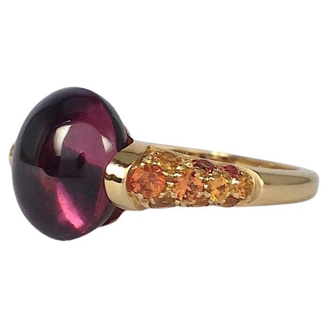 Anello in oro 18 Kt con gemma rodolite, zaffiro arancione, rosso, made in Italy
Questo anello in oro rosso ha un taglio a rodolite cabochon e lungo il lato sono presenti dei  totale di 0,54 carati di zaffiri arancioni.
Questo anello è stato