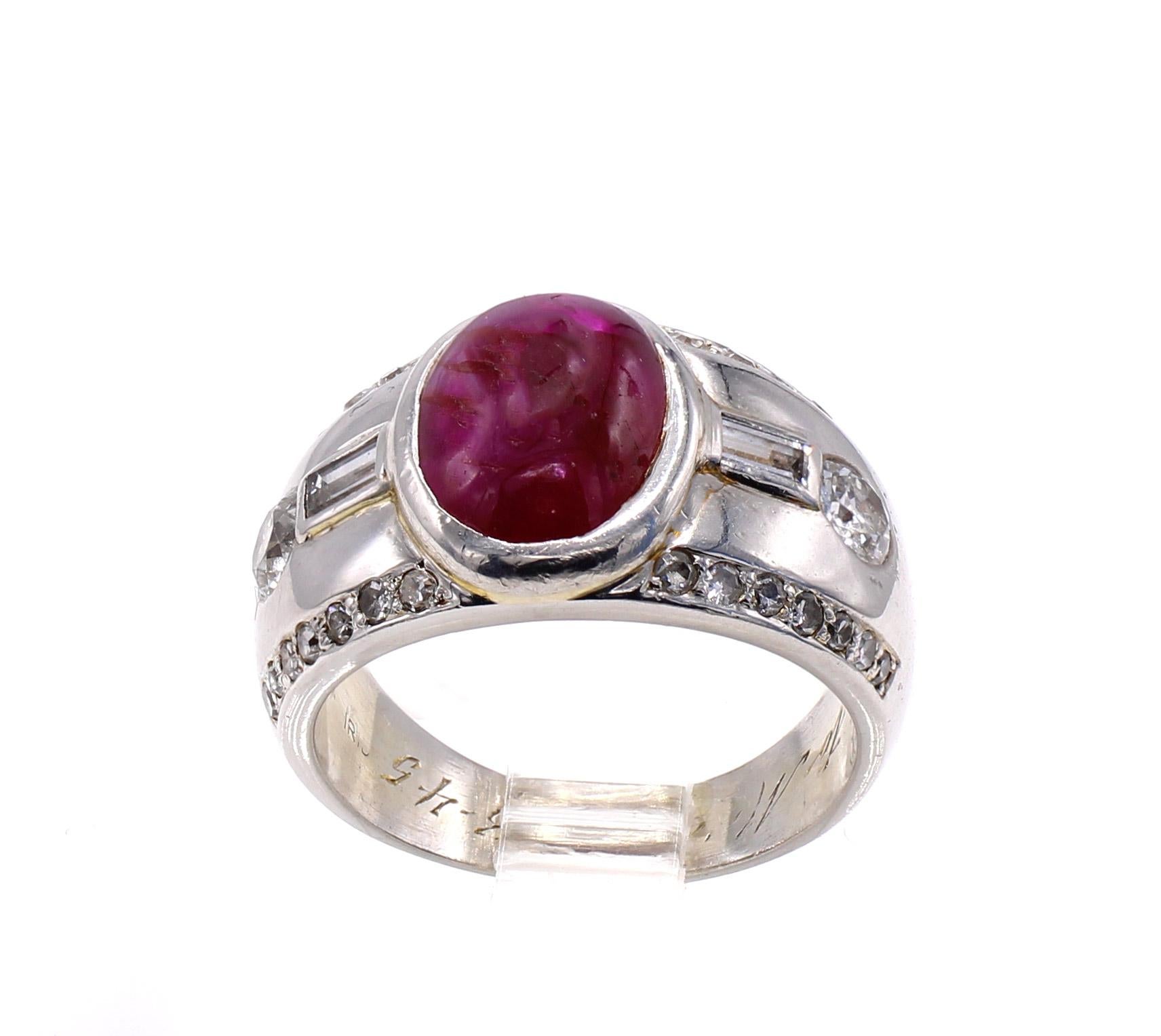 The centerpiece of this well handcrafted platinum Retro ring from ca 1945 is a pigeon blood red cabochon ruby estimated to weigh approximately 3.60 carats. The bezel set ruby is flanked by a baguette cut and one Old European Cut diamond on either
