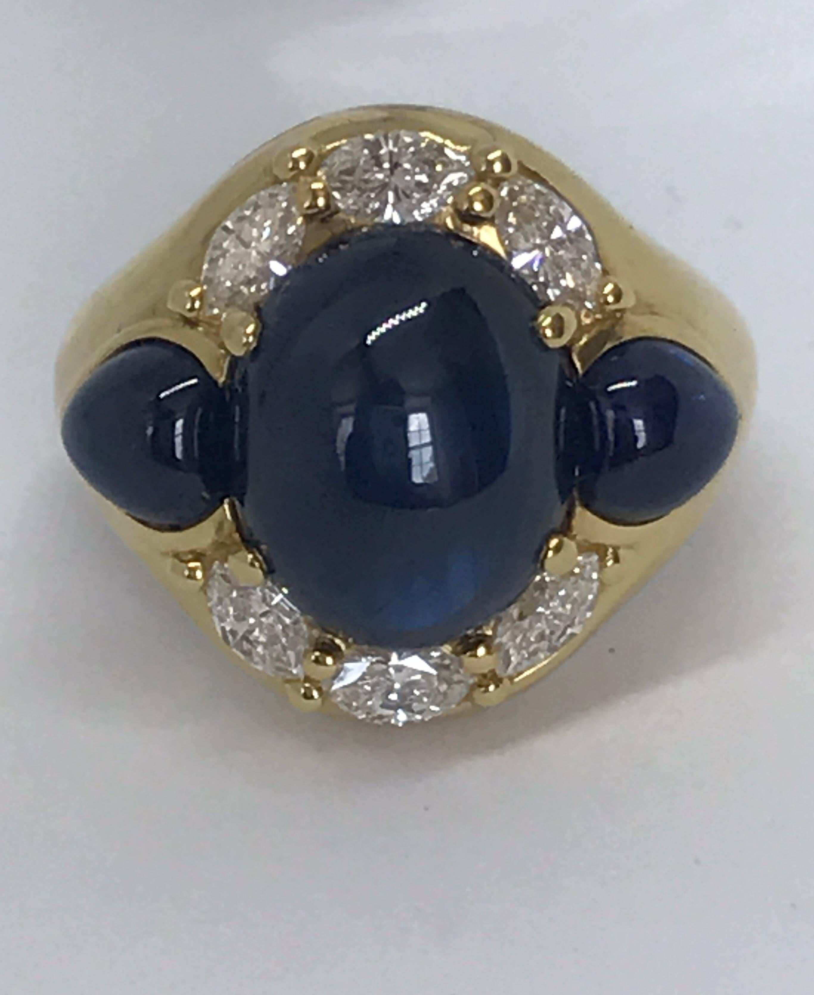 A cabochon sapphire and diamond 18k gold cocktail ring.  A central cabochon sapphire which measures 12.5 x 10mm  about 6.5cts is flanked by two pear shaped smaller sapphires each of  6mm x 5mm and surrounded by 0.8cts of diamonds, VS1 G/H Colour. 