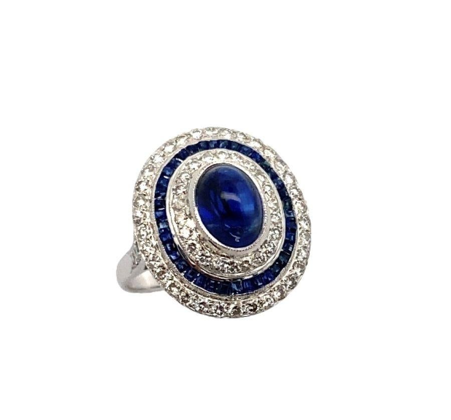 Cabochon-Cocktailring mit Saphir und Diamant. Ein Ring mit einem Cabochon-Saphir in der Mitte, umgeben von Halos aus Diamanten im Rundschliff und Saphiren im Baguetteschliff.

Ringgröße: 6.75

Kostenfrei anpassbar 

Metall-Typ: Platin
