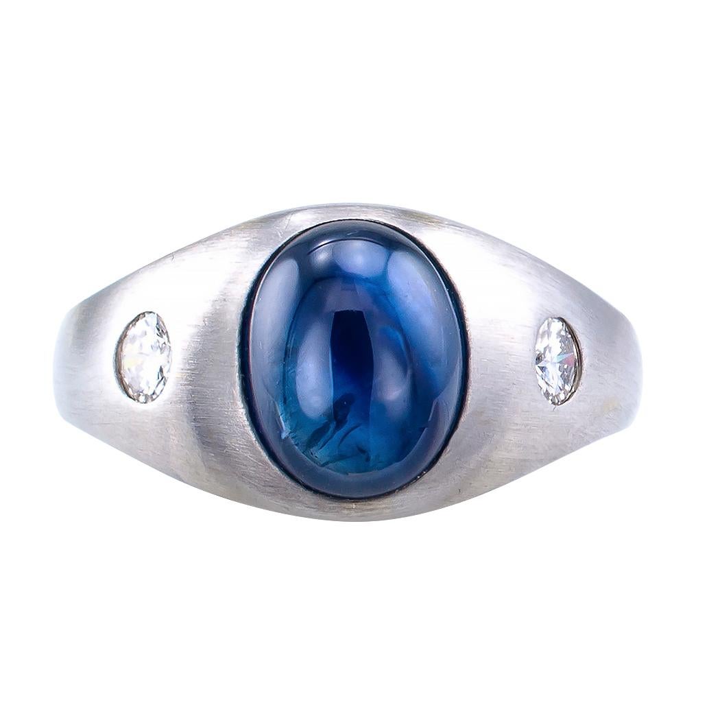 Midcentury cabochon sapphire and diamond gentleman’s white gold ring circa 1950.  Showcasing a blue, oval cabochon sapphire weighing approximately 4.00 carats, burnished-set between a pair of similarly set round, brilliant-cut diamonds totaling