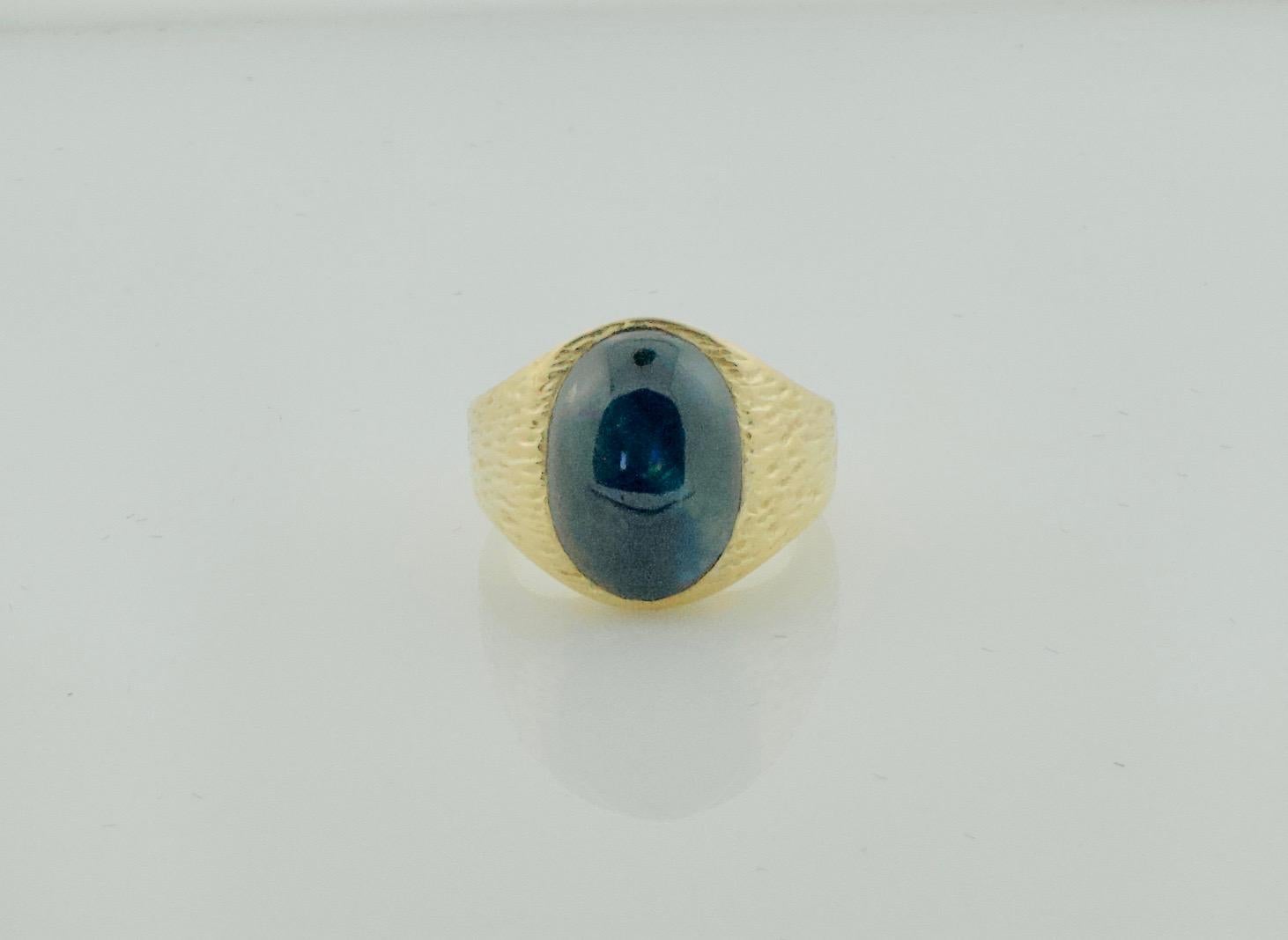 Cabochon Sapphire Pinky Ring with Bark Finish in Yellow Gold
One Cabochon Sapphire Weighing 15.00 carats approximately 16mm x 11mm x 8.5mm
Dark Blue with a hint of a star
Great For Flexing 
Size 8 1/4
