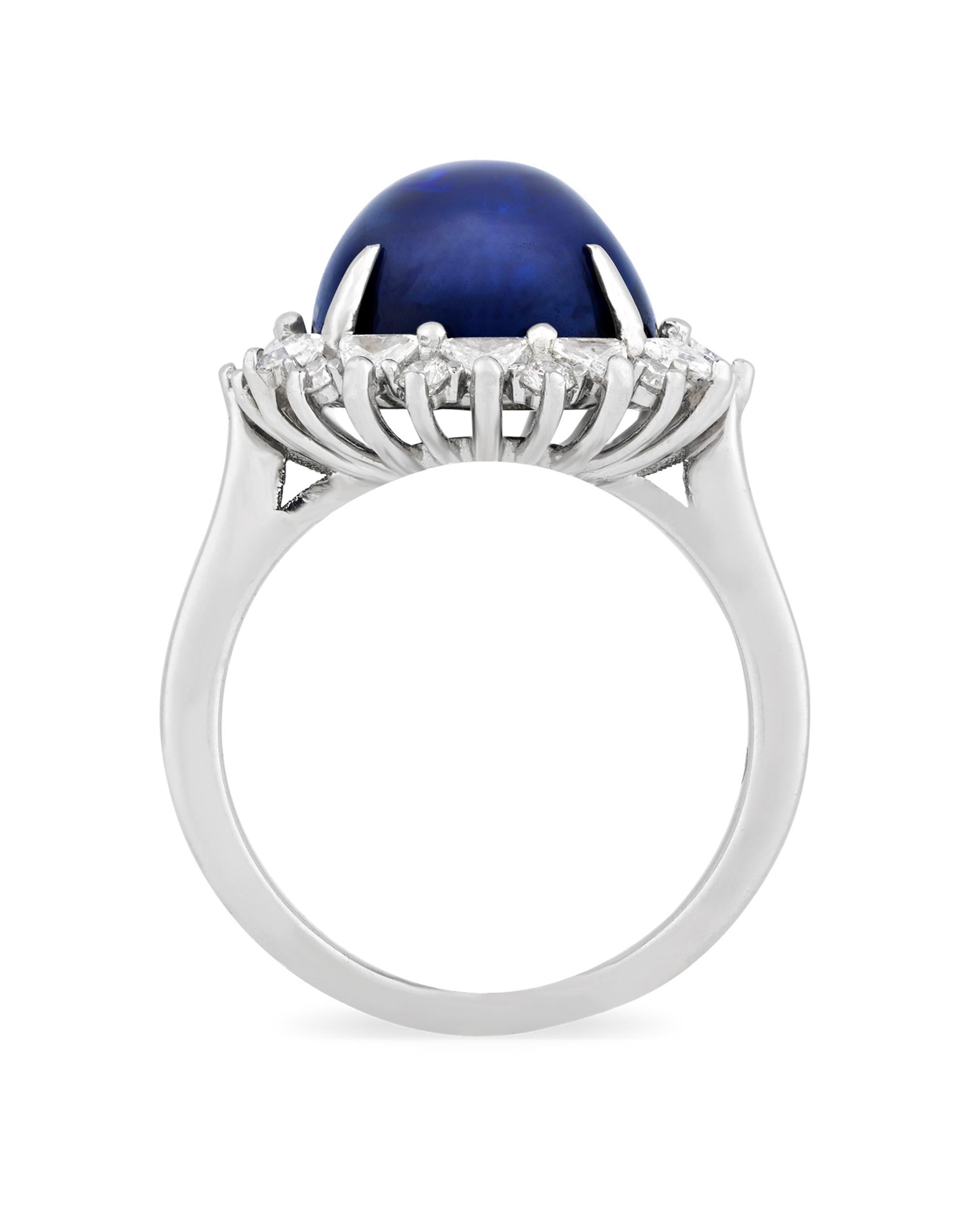 A stunning 11.72-carat cabochon sapphire rests at the center of this stylish ring. Deep and vibrant in color, the cushion-shaped jewel is accentuated by a halo of brilliant white diamonds totaling 0.67 carat, providing a brilliant contrast and