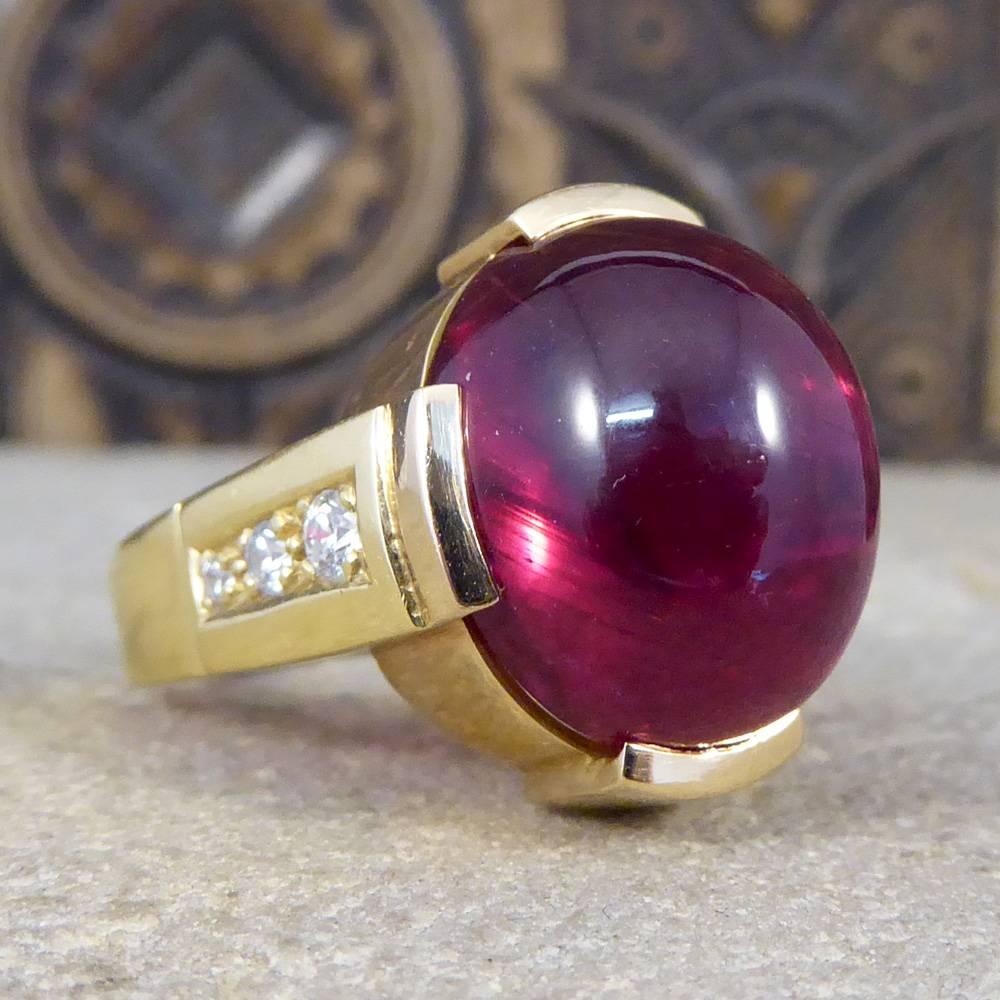 This stand out Contemporary Ring features ones large Cabochon Tourmaline showing deep red/fuchsia colours. With a geometric rectangular four claw settings and Diamonds set down the shoulders this is truly a show stopping piece with the makers mark