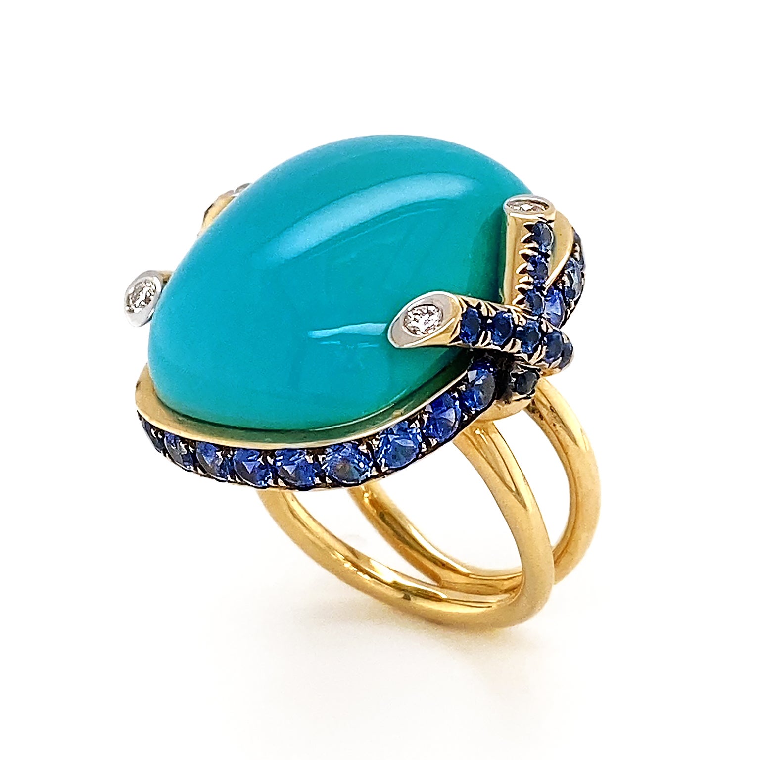 Striking blue of turquoise is the climax of this ring. The polished cabochon is bezel set in 18k yellow gold, which features two inter crossing diamond tipped strands on each side. Sapphires rotate in the bezel setting for a glimmering tranquil