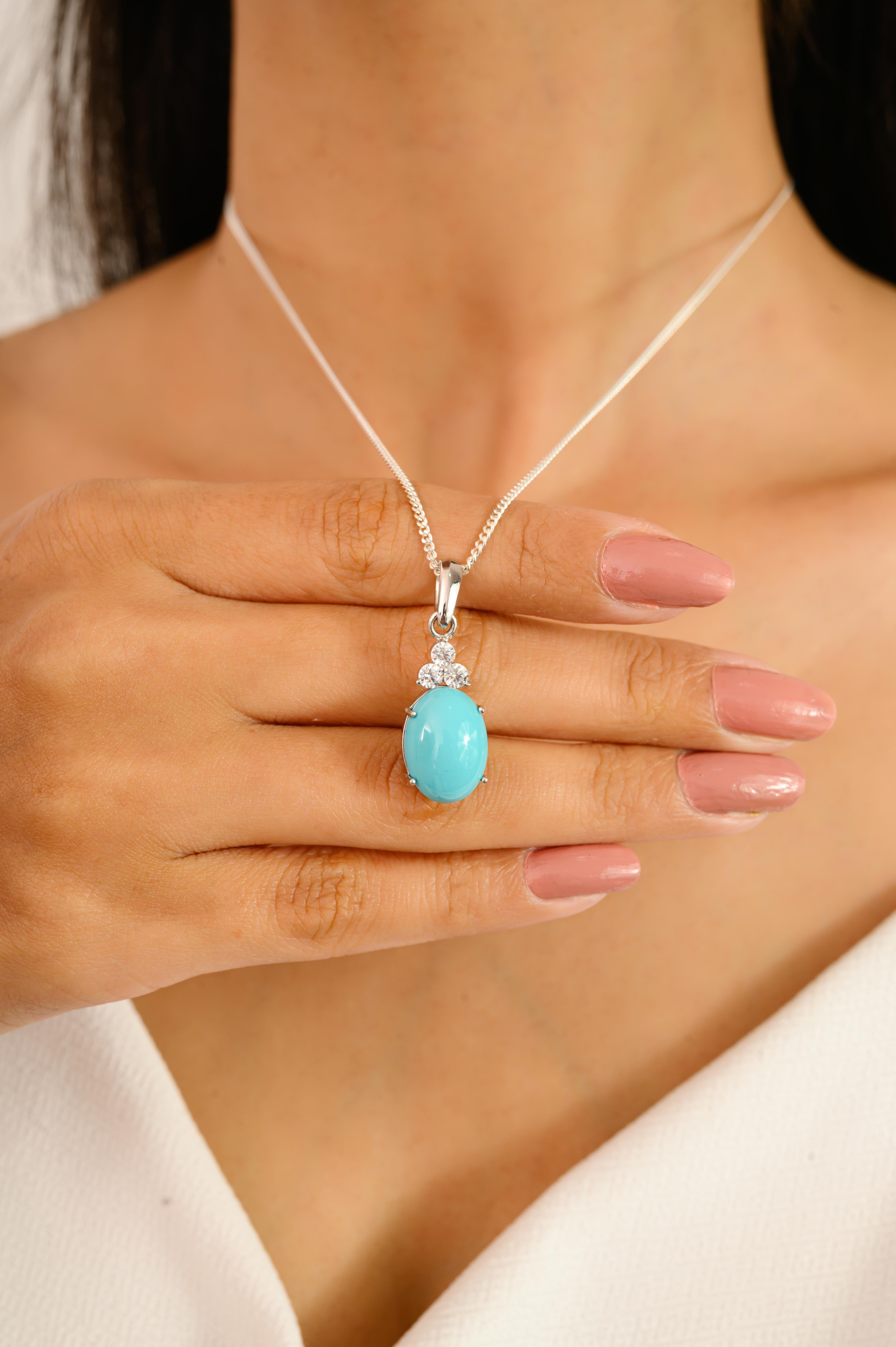 This Cabochon Turquoise Unisex Drop Pendant with Cubic Zirconia in Sterling Silver pendant features a vivid oval cabochon turquoise set in sterling silver, crowned by a trio of brilliant-cut zircon. The vibrant blue gemstone adds a bold yet serene