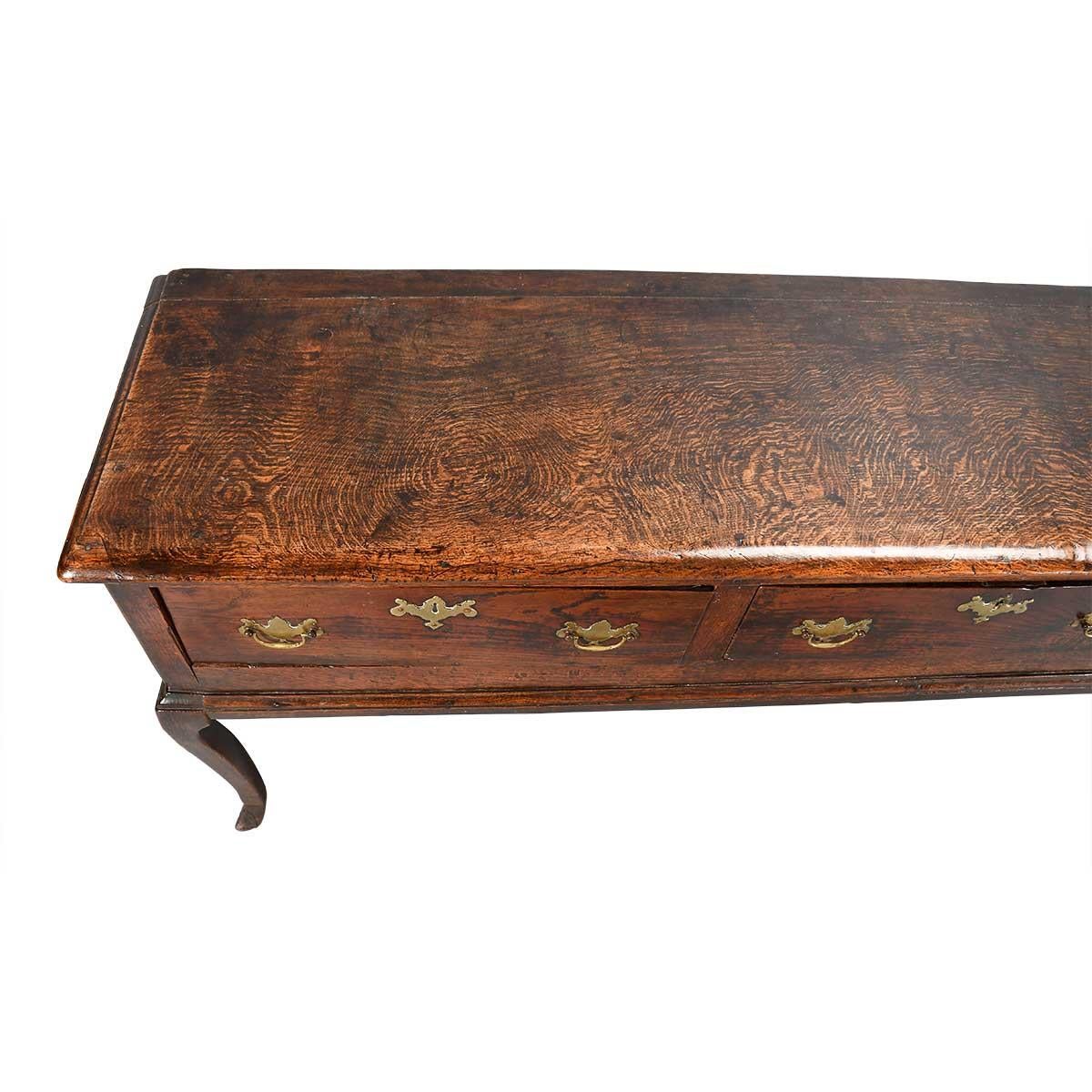 An oak three-drawer dresser with terrific color and patina. The stunning pattern of medullary rays indicate that the top is a superb quality piece of quarter-sawn timber. Each cabriole leg features a collar just above the squared pad foot. Brasses