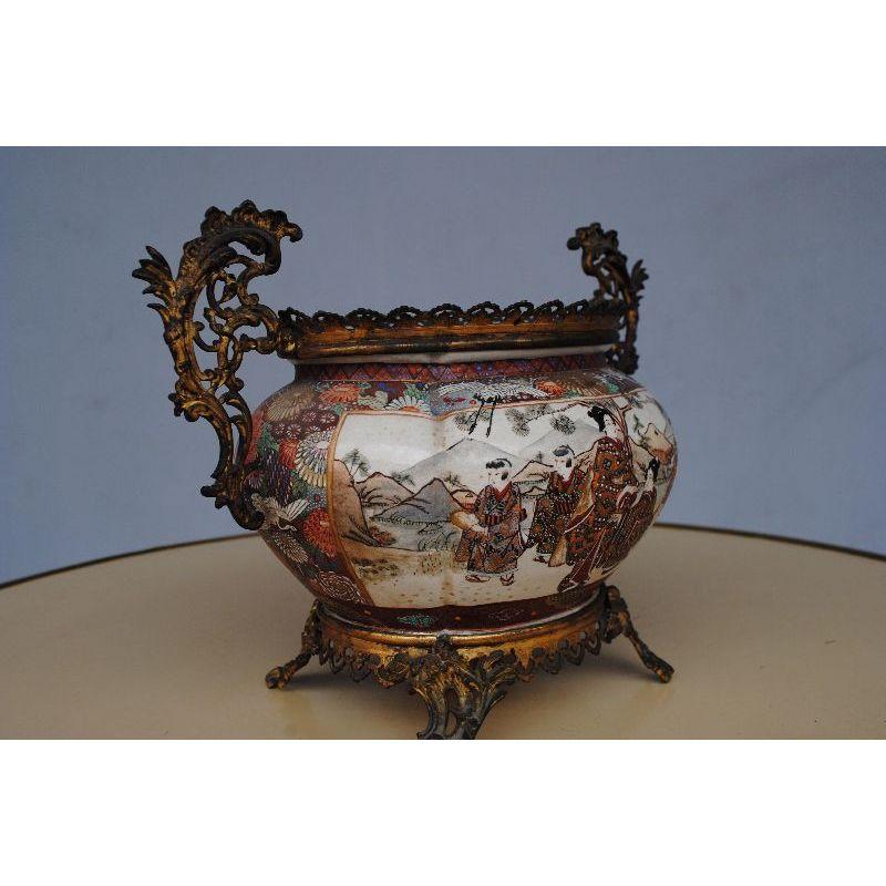 Antique Satsuma pot cover from Japan, late 19th century, with bronze frame decorated with elegant women on the edge of a lake. Dimension height 21 cm for a total width (handles included) of 34 cm.

Additional information:
Material: bronze,