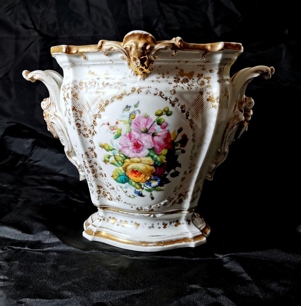 Elegant cachepot in French porcelain, the shape is very particular and graceful, on the sides, there are two rich decorations with grotesque masks, as well as in the central part of the upper edge, it is completely hand-painted with beautiful