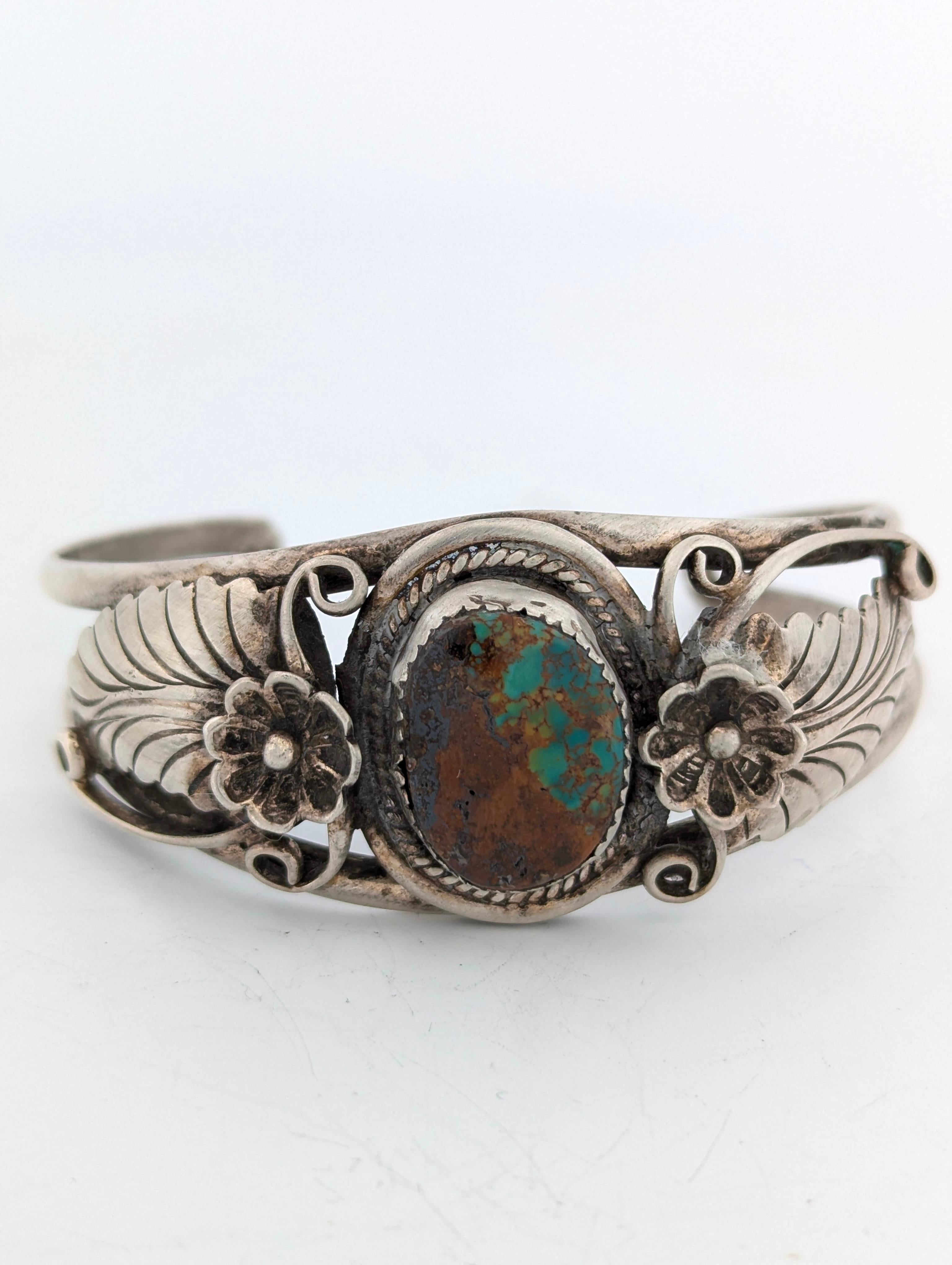The Cactus Bloom cuff bracelet is a vintage sterling silver piece featuring a striking blue and brown turquoise cabochon. This handmade cuff is stamped 
