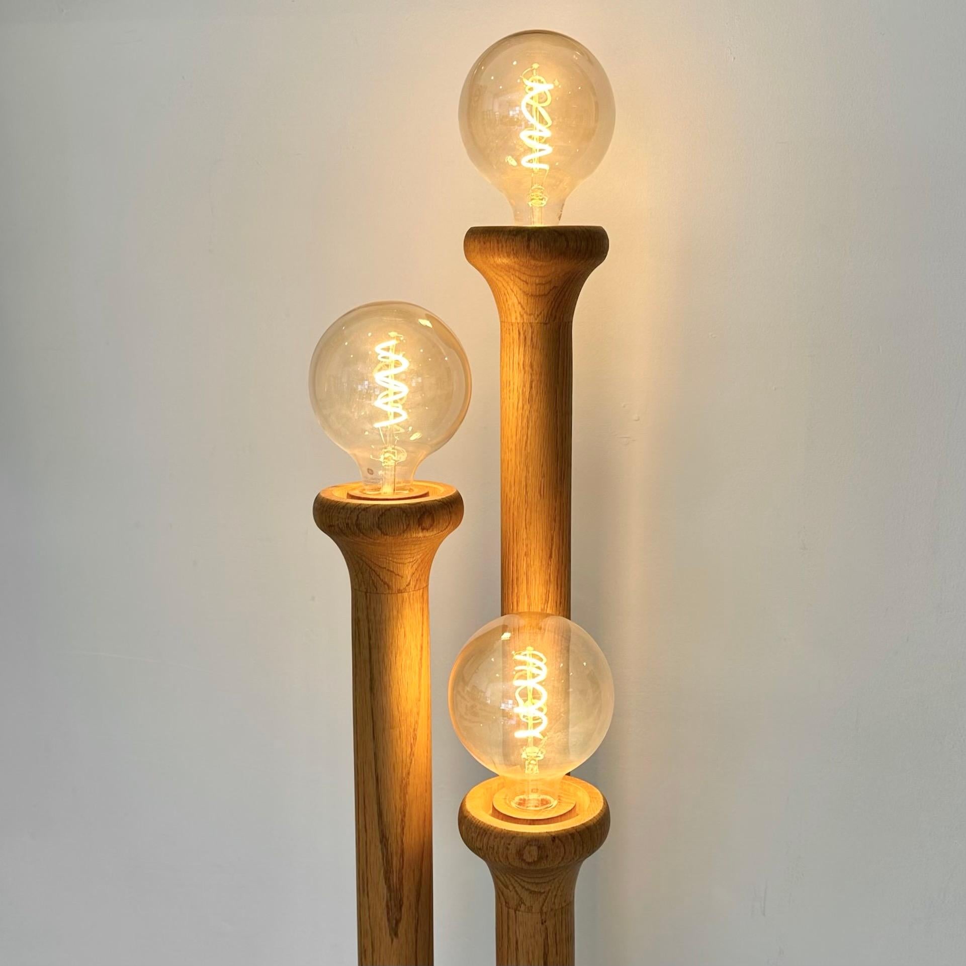 Stunning floor lamp made of California pine. Manufactured in the style of Modeline in the 1970s. Three wooden stems protrude from the lamps wooden base, each rising to a different height. Features three original glass globes atop each stem, with