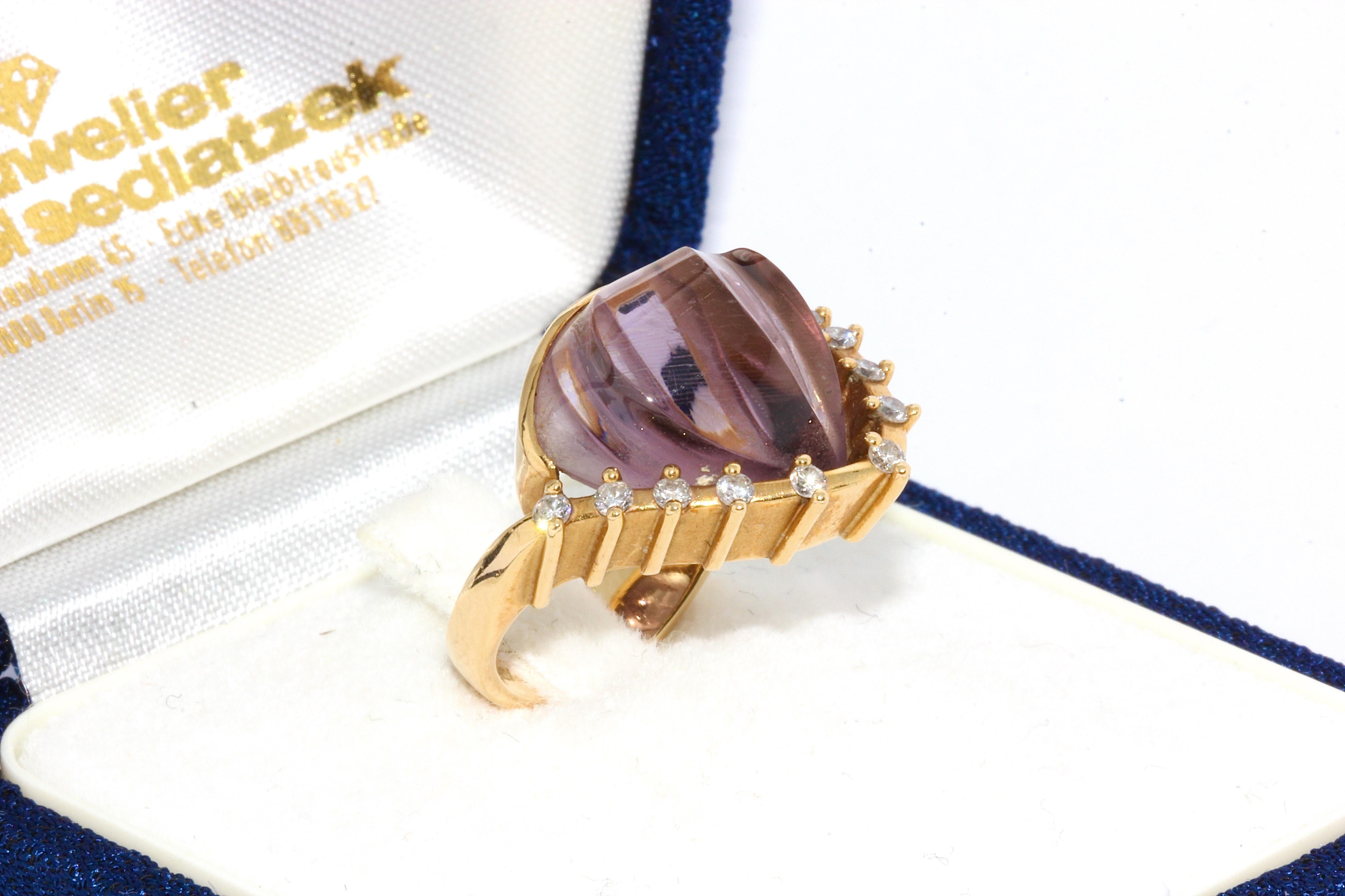 Enchanting 18 karat gold ring set with large amethyst and diamonds.
By famous jewelry designer Cadeaux.

18 karat yellow gold, hallmarked
Large, elegantly cut amethyst (shell-shaped)
Set with 10 small diamonds

Including certificate of