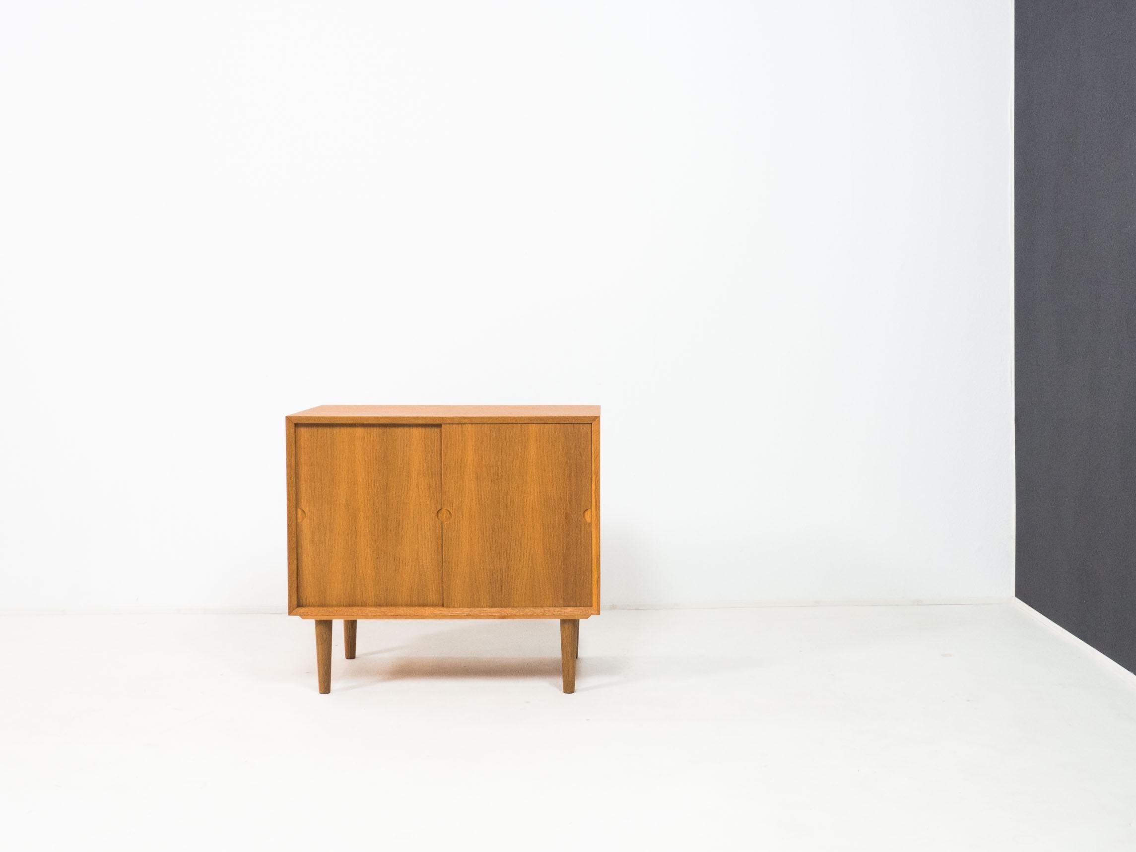 Sliding door cabinet with tapered feet designed by Poul Cadovius for Cado, Denmark in the 1960s.

This cabinet has oak veneered sides, top and sliding doors and has solid oak edges and feet.

The condition of the cabinet is good. There are