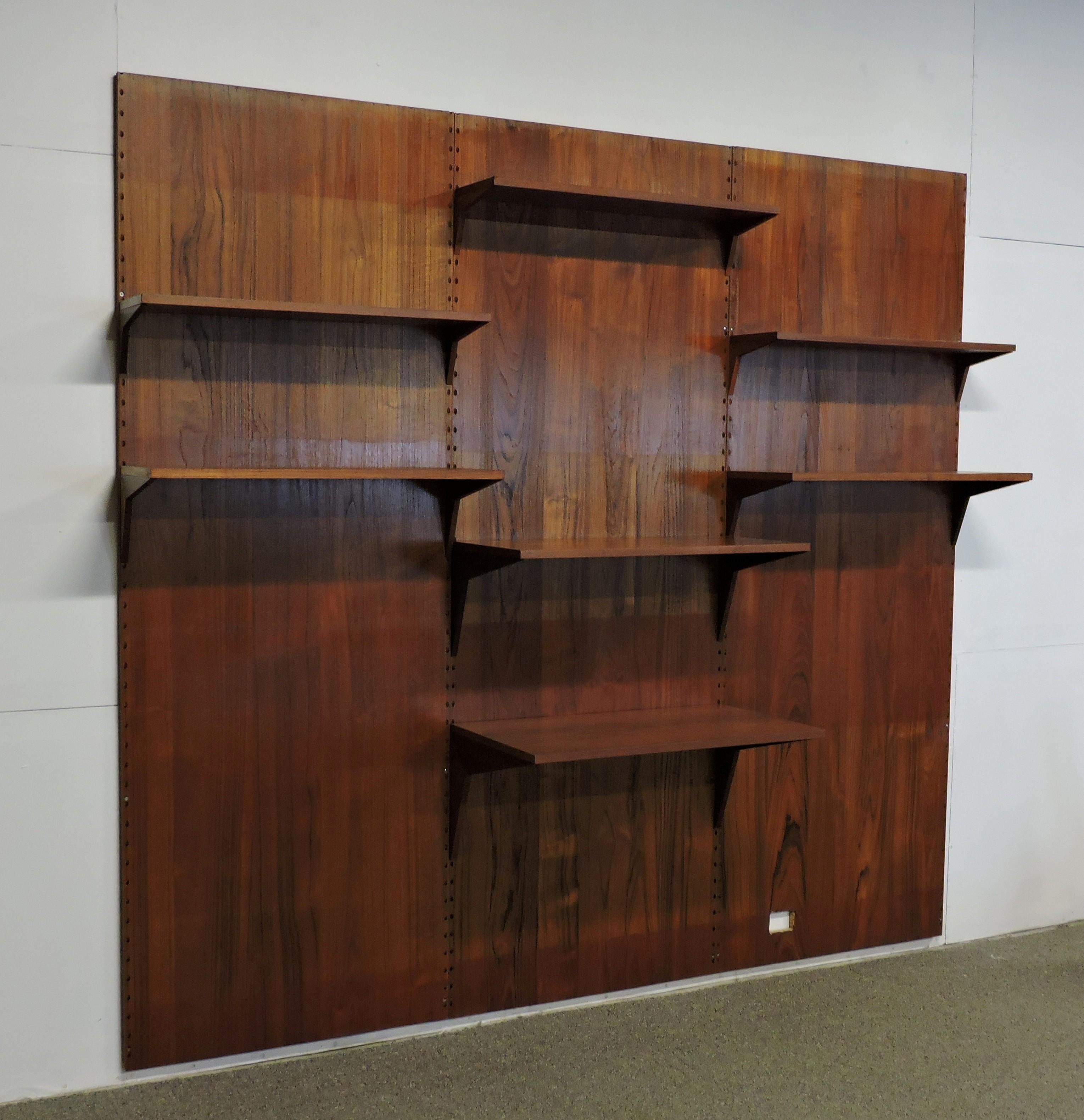 Large three bay teak Cado wall system designed by Poul Cadovius and made in Denmark. This unit has beautiful color and a nice active grain pattern, and includes three wall panels for installation and 7 shelves, the largest of which could be used as