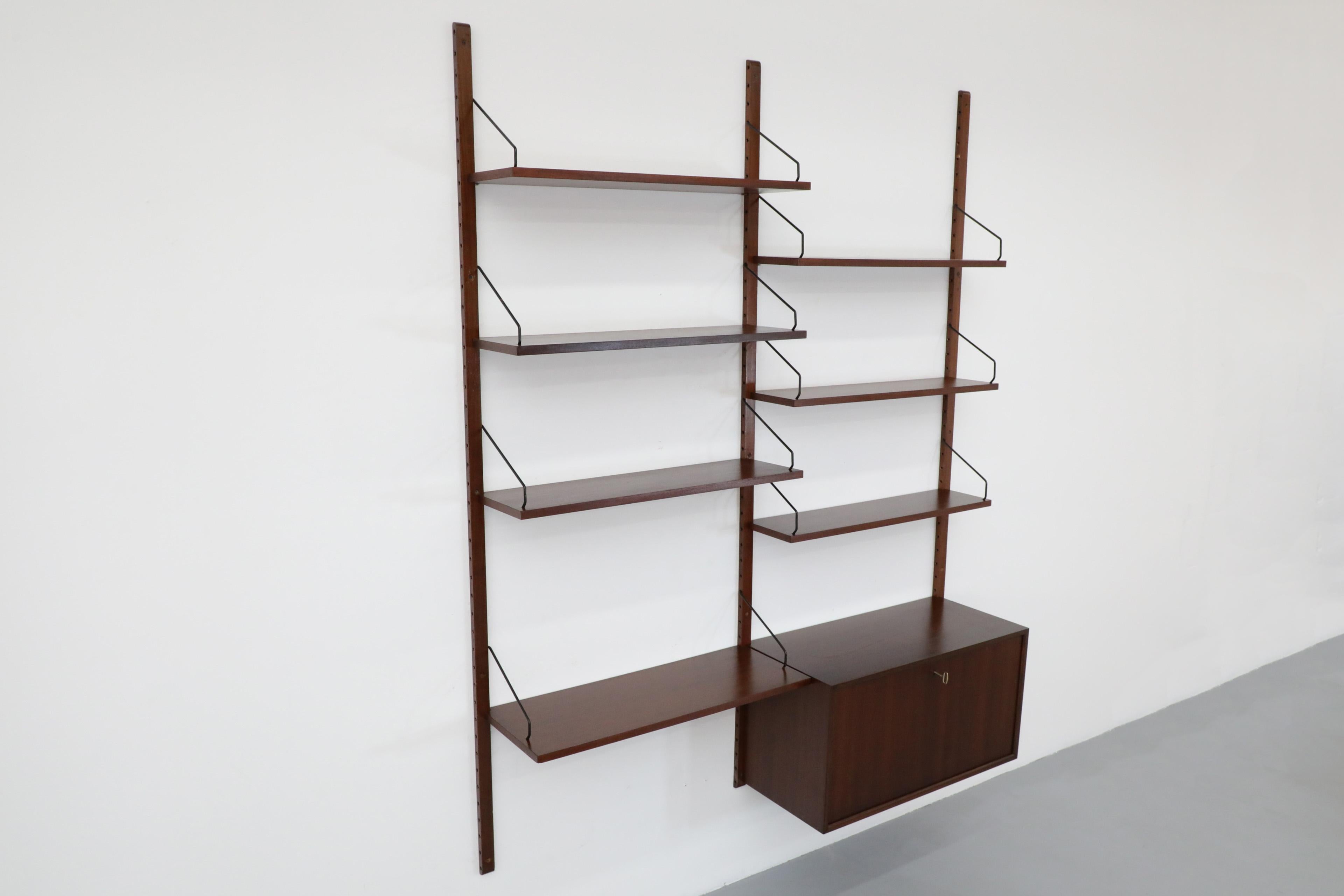 Royal System wall mounted two section Rosewood adjustable shelving unit with locking cabinet and desk shelf by Poul Cadovius. The shelves can be arranged in a number of ways with six small shelves (8