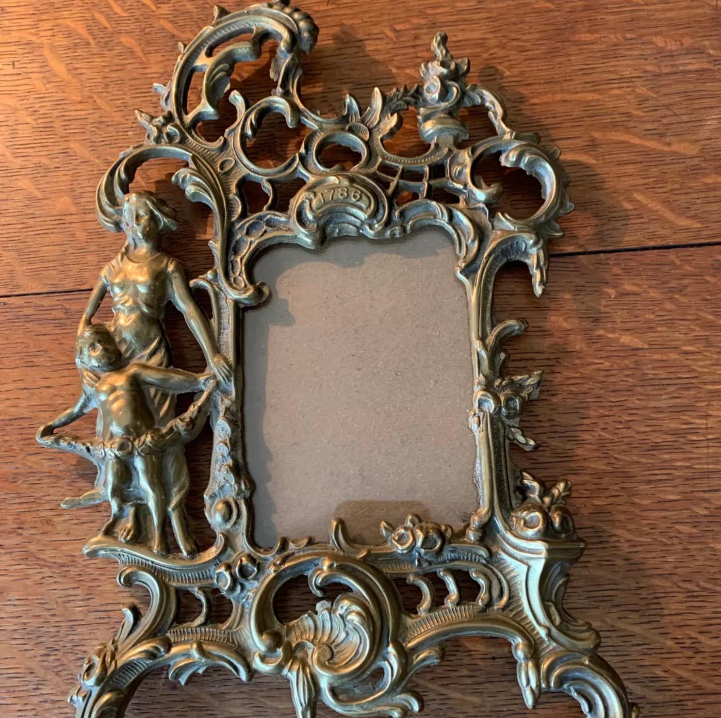 Cadre louis XV en laiton doré finement ciselé à riche décor rocaille de fleurs et feuillage stylisé, dame et putti à la guirlande et année 