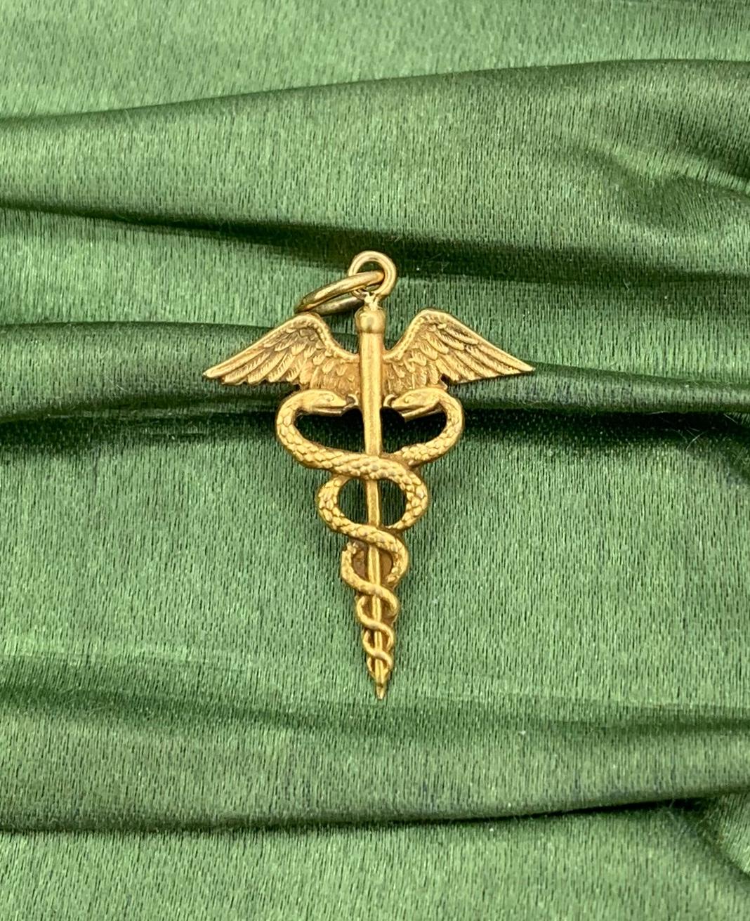 INDULGE IN A WONDERFUL CADUCEUS PENDANT WITH ENTWINED SNAKES IN 10 KARAT YELLOW GOLD.
The caduceus is a symbol that features two snakes wrapped around a staff, often with wings, and is associated with medicine, Hermes, and peaceful dispute