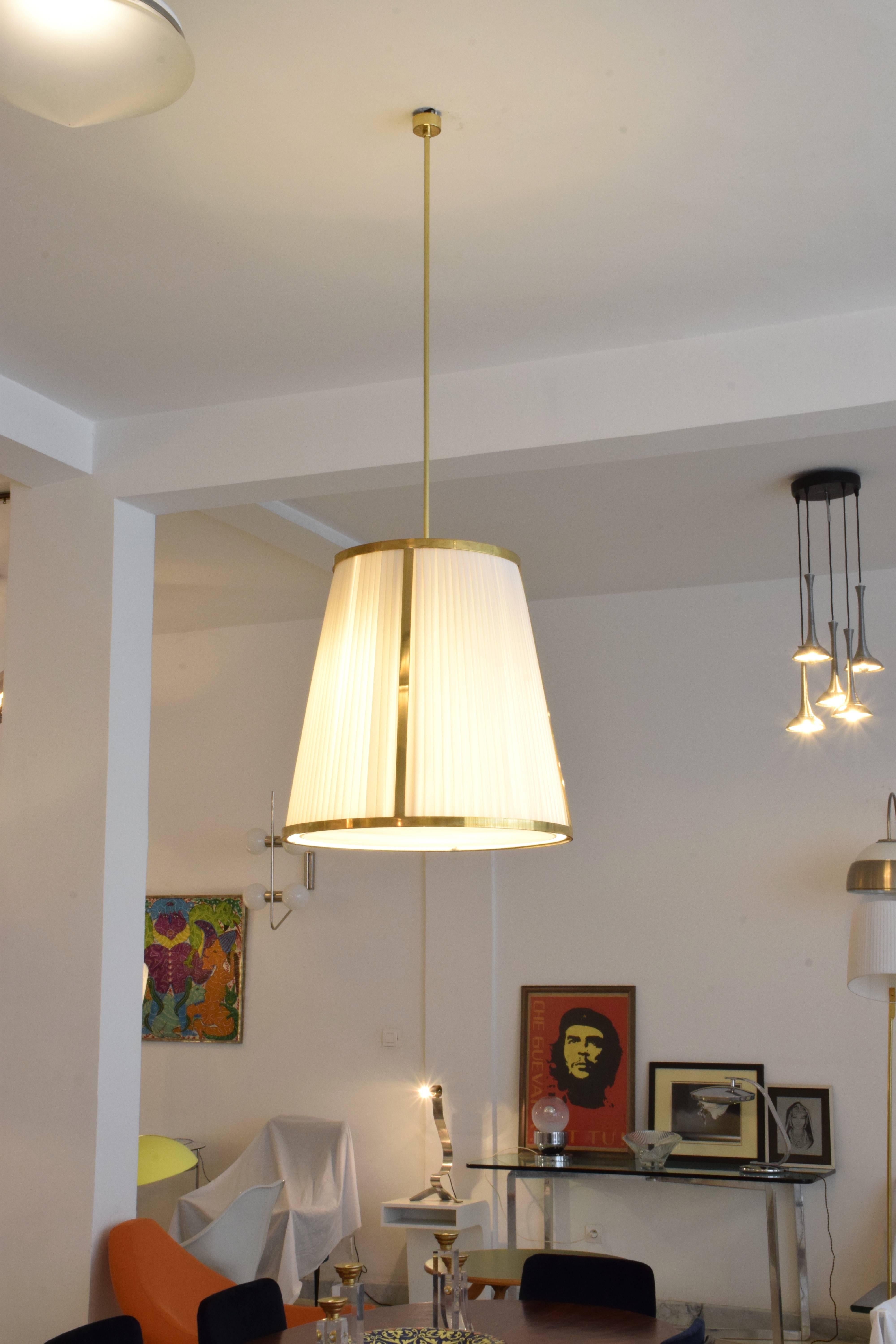  The contemporary handcrafted made-to-measure pendant light fixture features an expertly handcrafted brass structure and a hand-pleated white fabric shade. This piece creates a warm and inviting ambiance, perfect for living areas or kitchen island