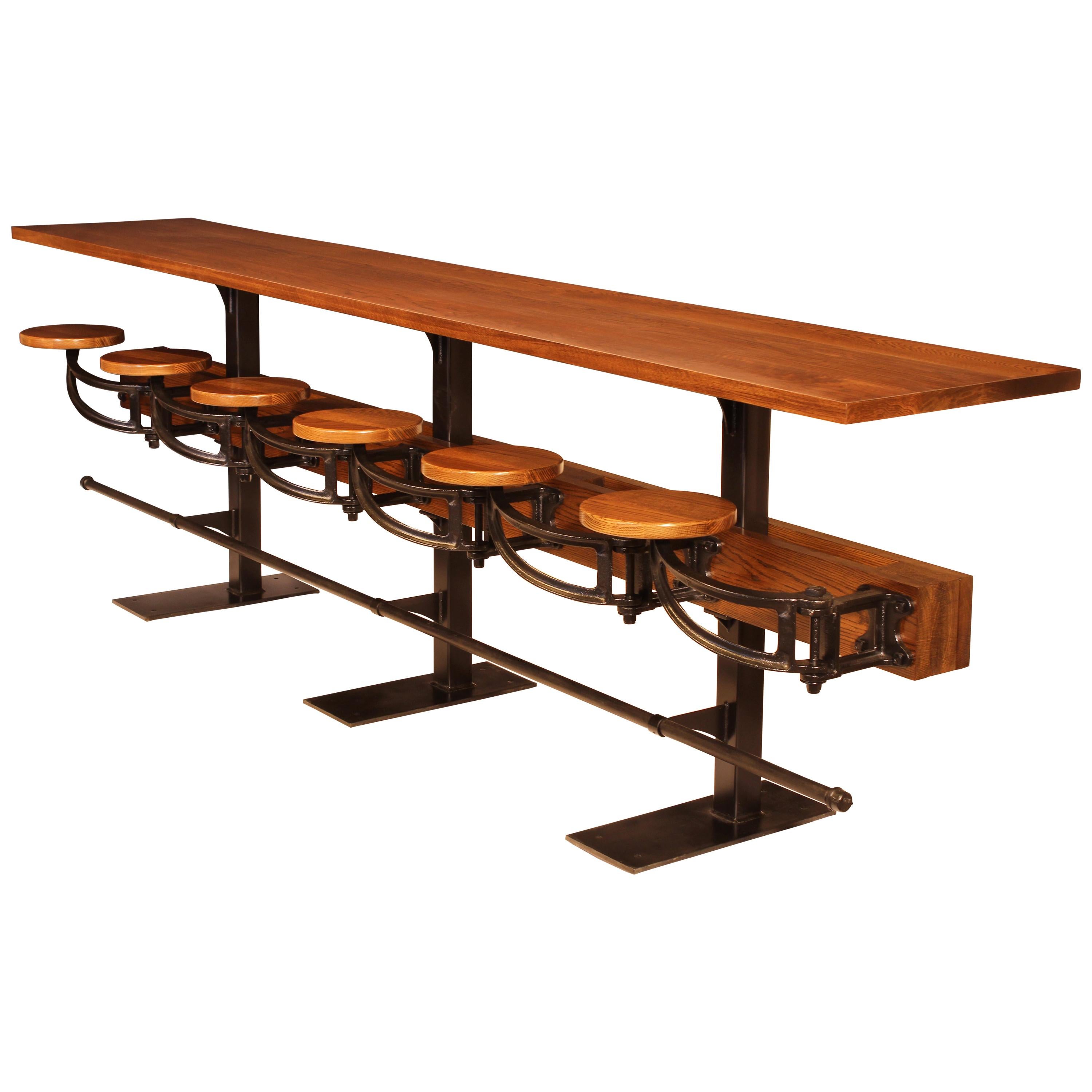 Counter height cafe wall table with attached cast iron swing-out seats. Example shown is red oak in a 12 foot length with six seats, three pedestals and foot rail. A great solution for adding additional seating to a wall section in your kitchen,