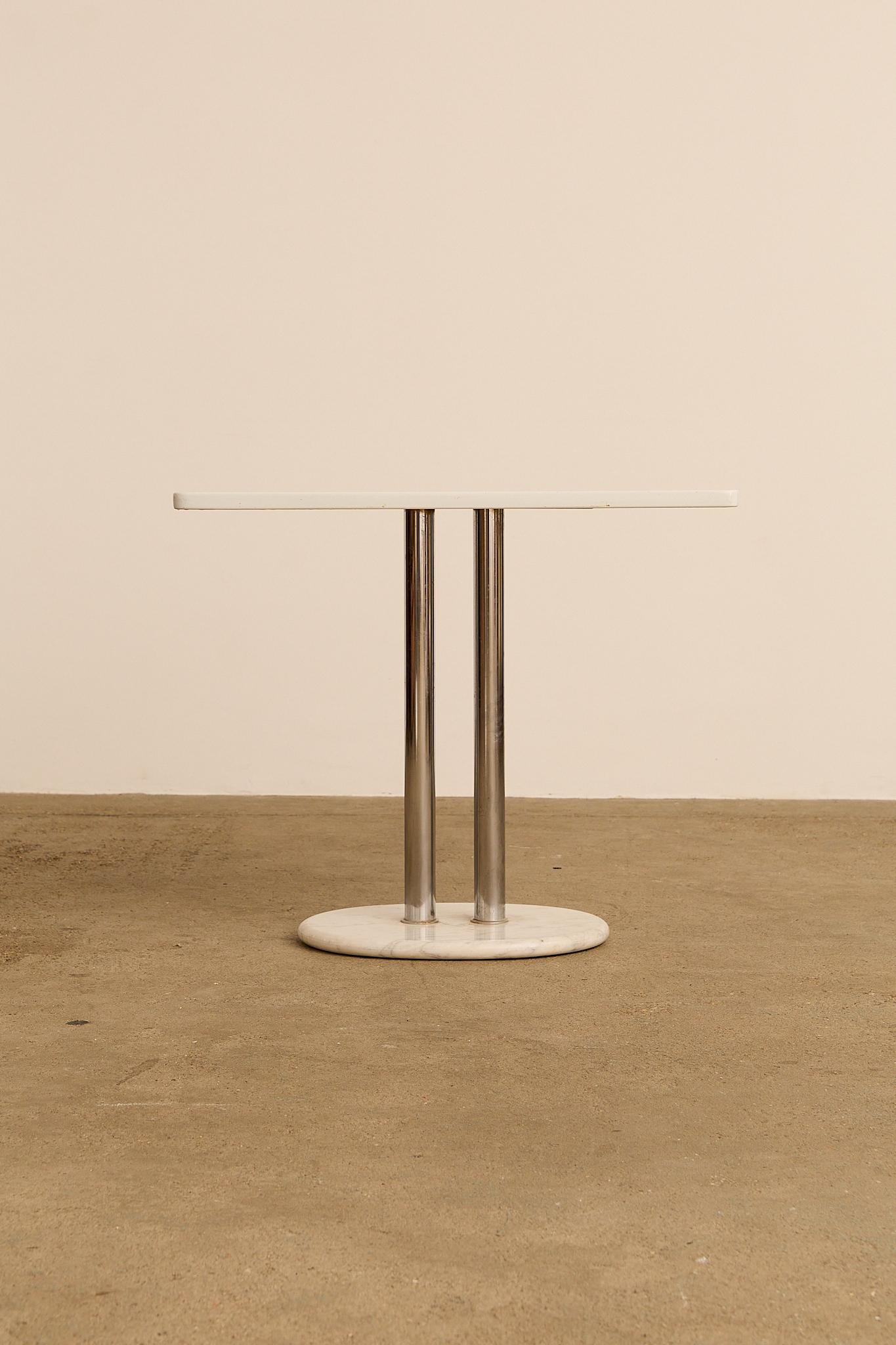 Table carrée conçue par Kazuhide Takahama en Collaboration avec Dino Gavina pour un projet d'hôtel à Bologne. La table présente un plateau en bois laqué, soutenu par deux pieds en acier poli enchâssés dans un socle ovale en marbre de Carrare. Sa