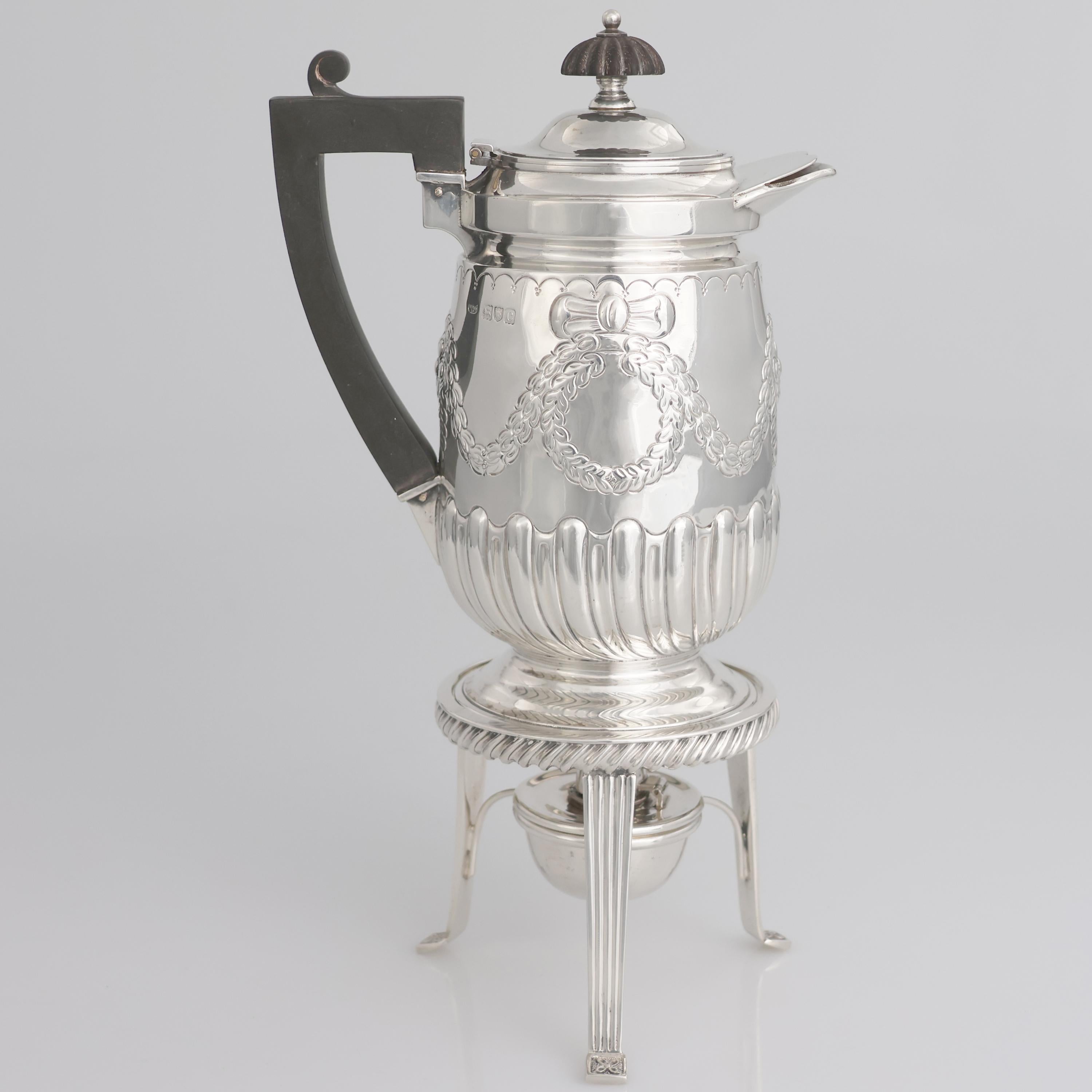 Descrizione
Caffettiera in argento sterling su supporto con bruciatore Regina Vittoria; Hawksworth, Eyre & Co Ltd; Londra, 1898
La caffettiera presenta una forma ovale allungata, con una base leggermente svasata e un corpo suddiviso in due sezioni