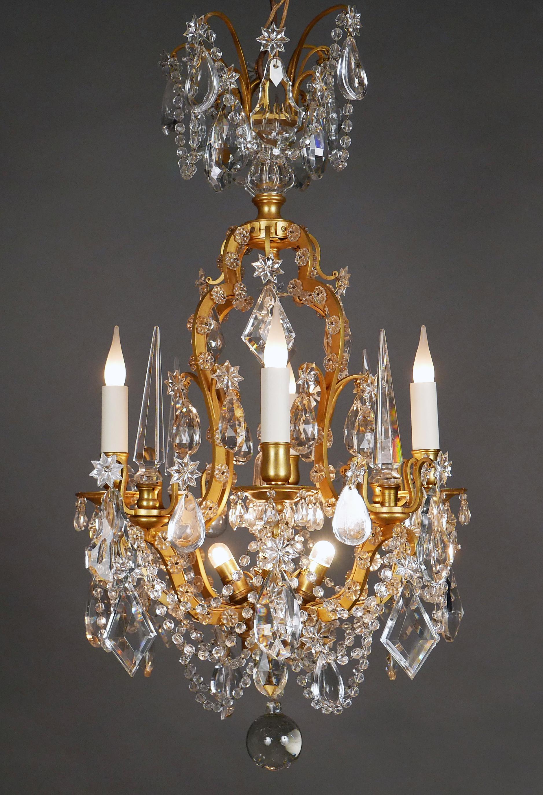 Charming Louis XVI style « cage » shaped chandelier in gilded bronze and cut crystal, with four lights. Many cut crystal pendants, daggers, prisms and flowers adorned the whole, connected with garlands of pearls. An indirect lighting system reveals