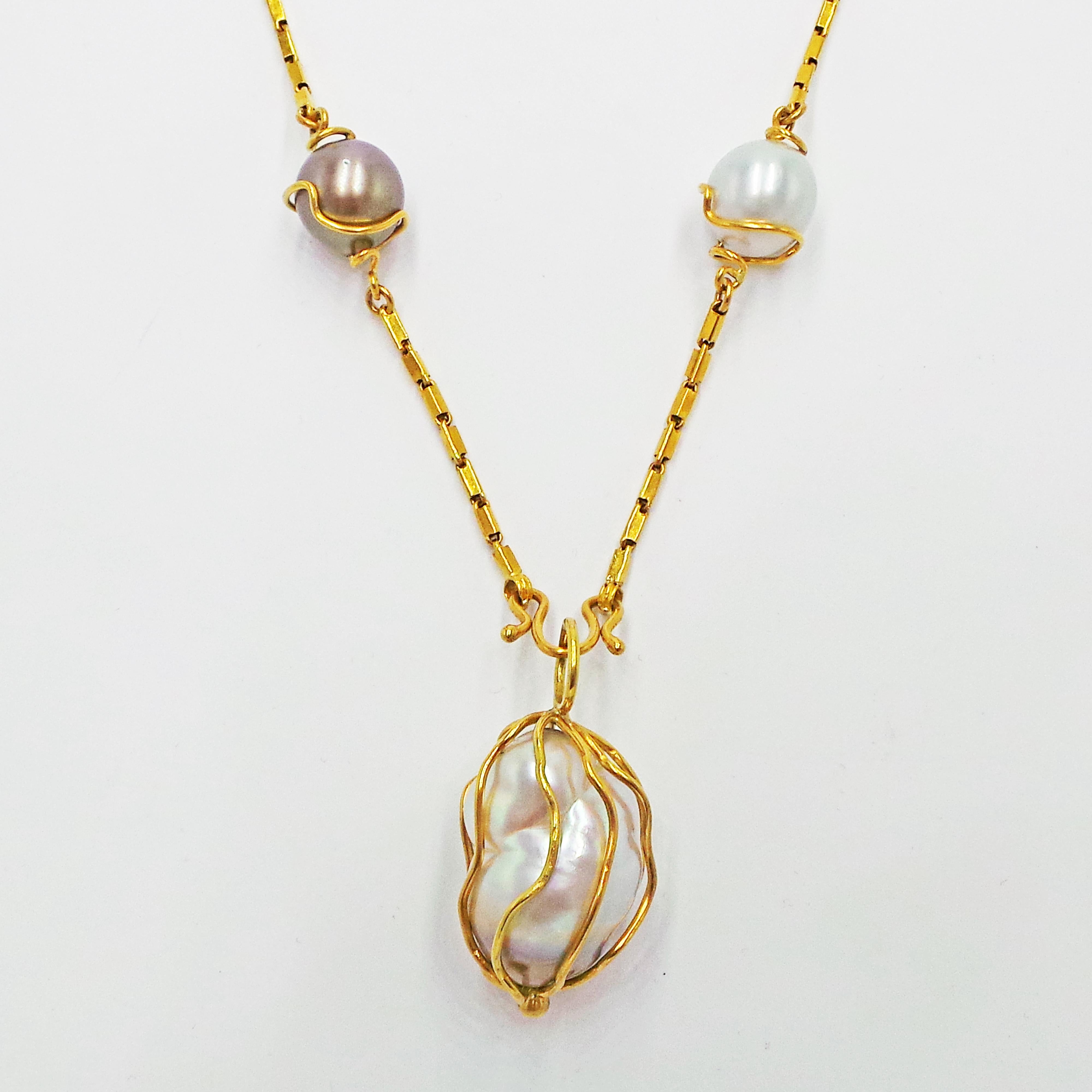 Large, impressive 28mm Baroque Pearl caged in a hand-fabricated, 22k yellow gold pendant on a 22k yellow gold Baht chain with six 13-13.5mm freshwater and Tahitian pearls all wrapped in 22k yellow gold. Necklace is 25 inches in length. Natural