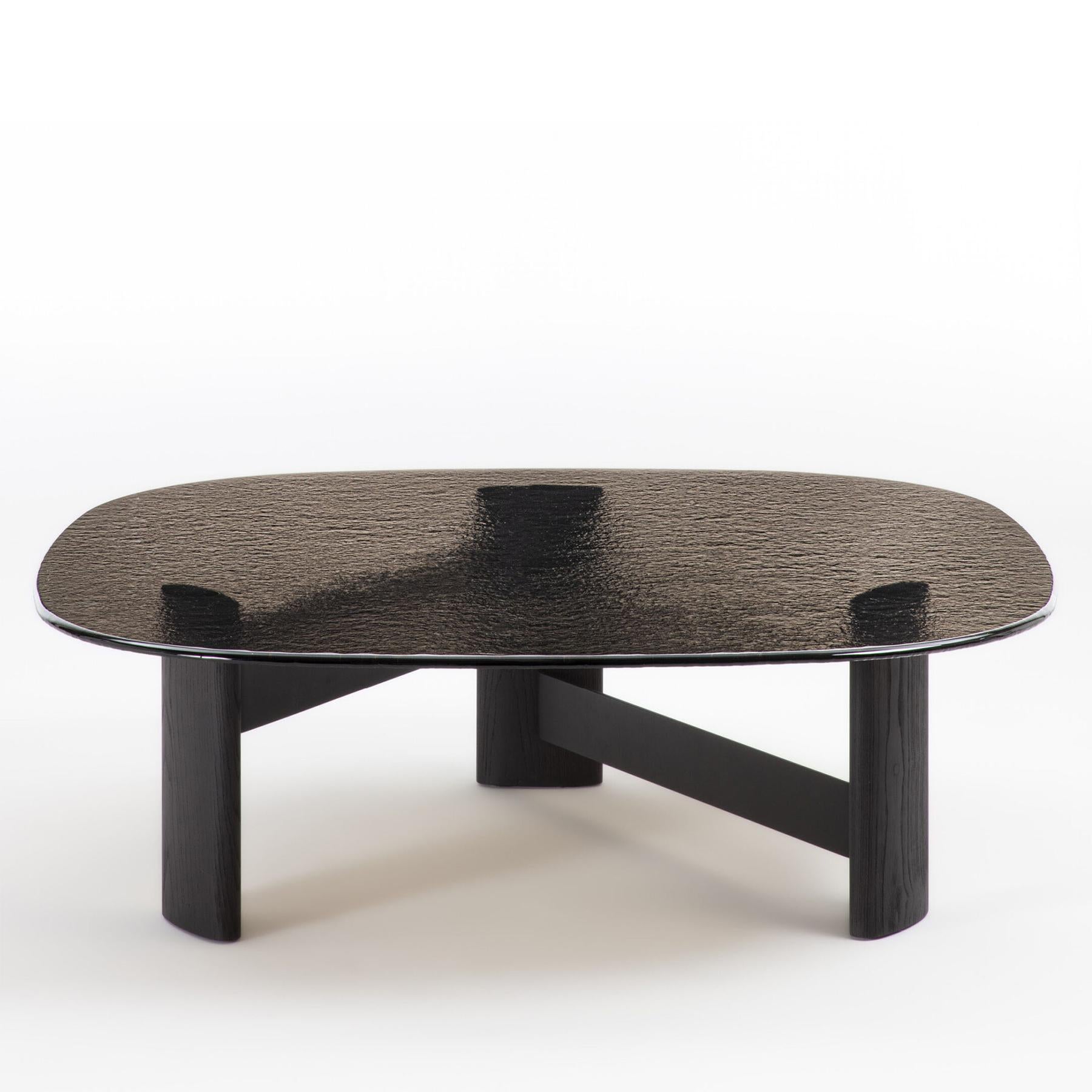 Table basse Cagliari Large avec structure de base en frêne massif
en finition brossée teintée foncée et avec des bandes de connexion en métal
en noir mat. Avec plateau en verre thermoformé en finition terre.
Également disponible sur demande en table