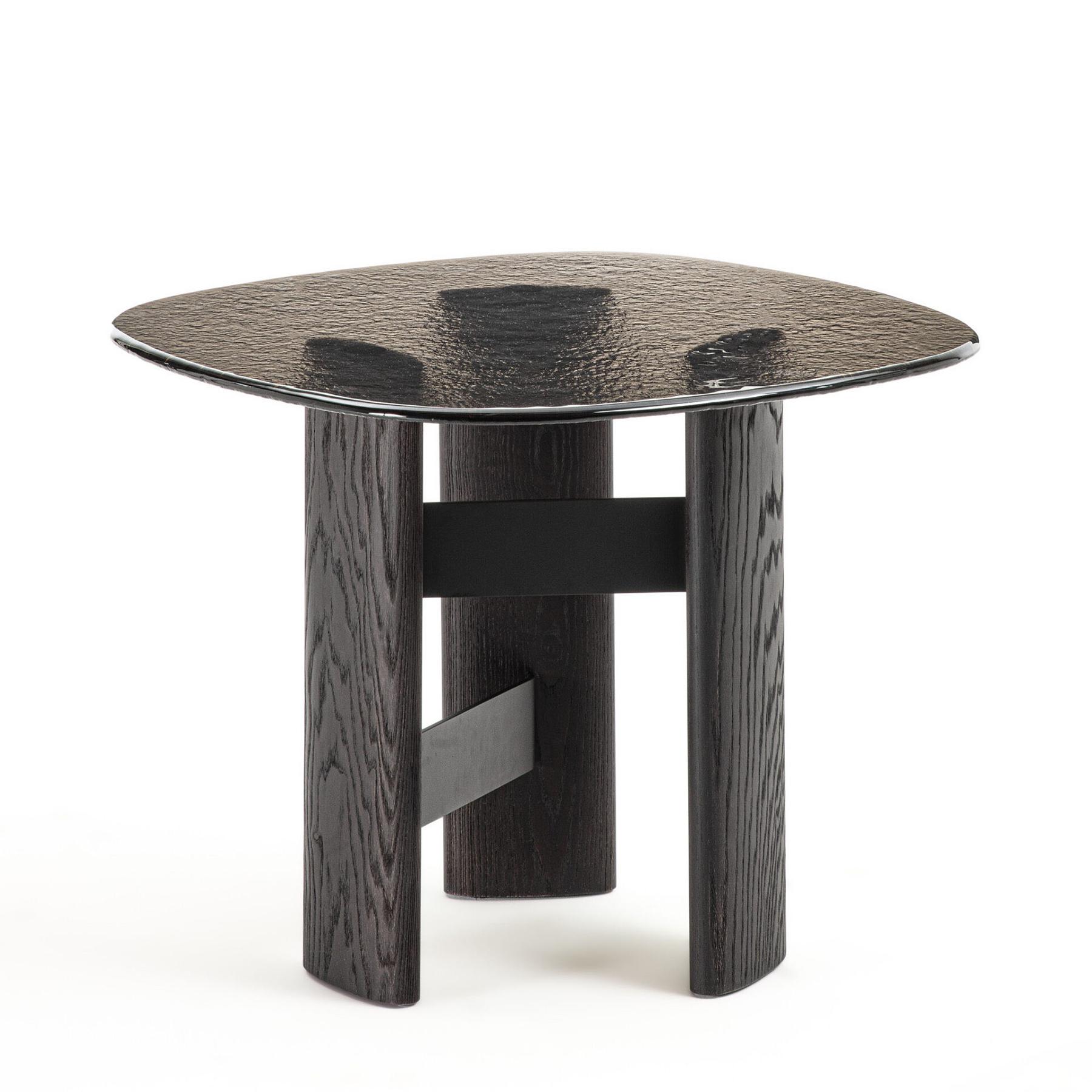 Table d'appoint Cagliari Medium avec structure de base en frêne massif
en finition brossée teintée foncée et avec des bandes de connexion en métal
en noir mat. Avec plateau en verre thermoformé en finition terre.
Également disponible sur demande en