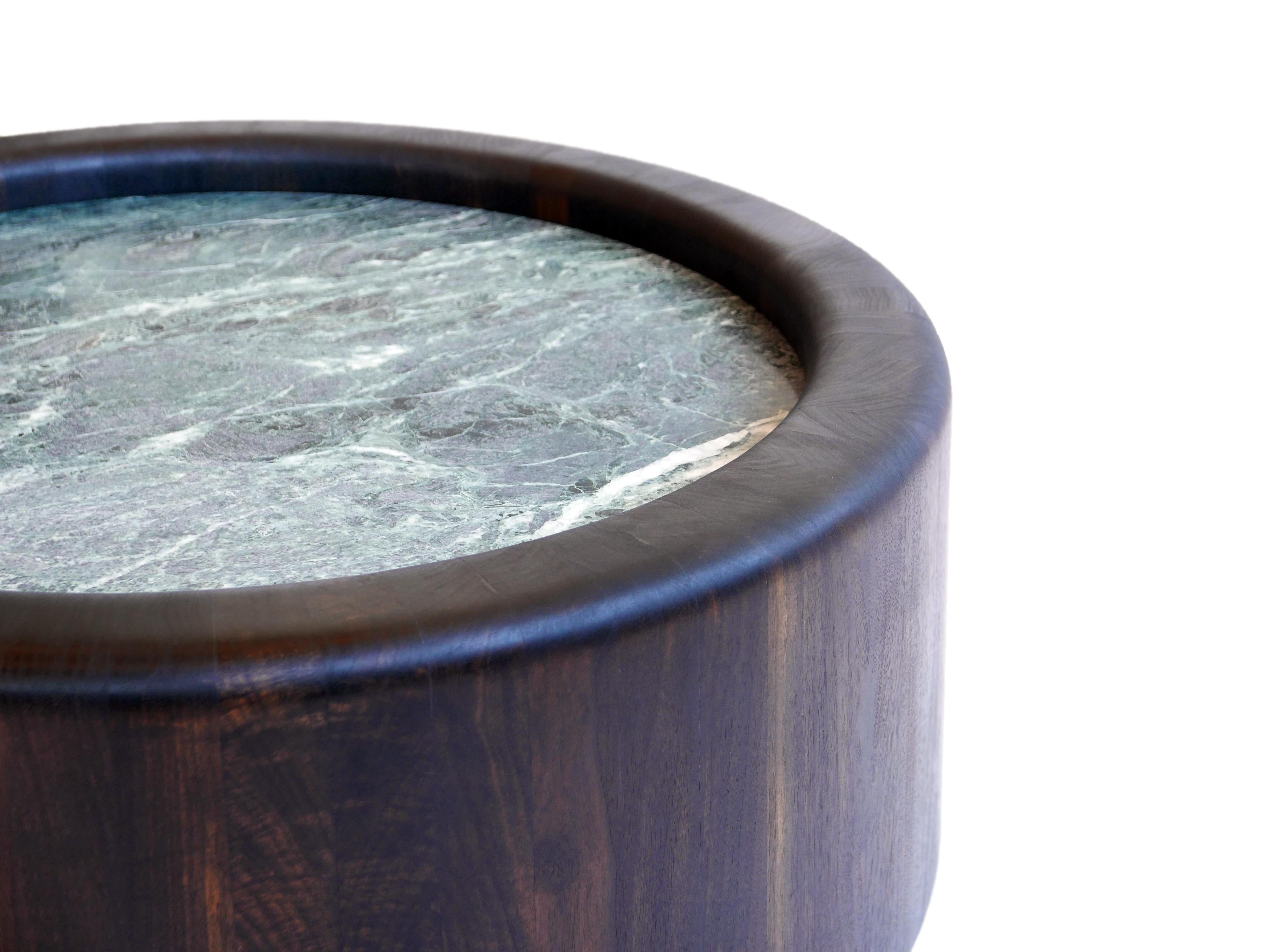 Les tables Caisson sont fabriquées en bois dur massif assemblé et façonné selon des techniques de tonnellerie traditionnelles. À l'intérieur du bord roulé de la forme en bois repose une plaque de marbre massif faisant office de plateau de table,