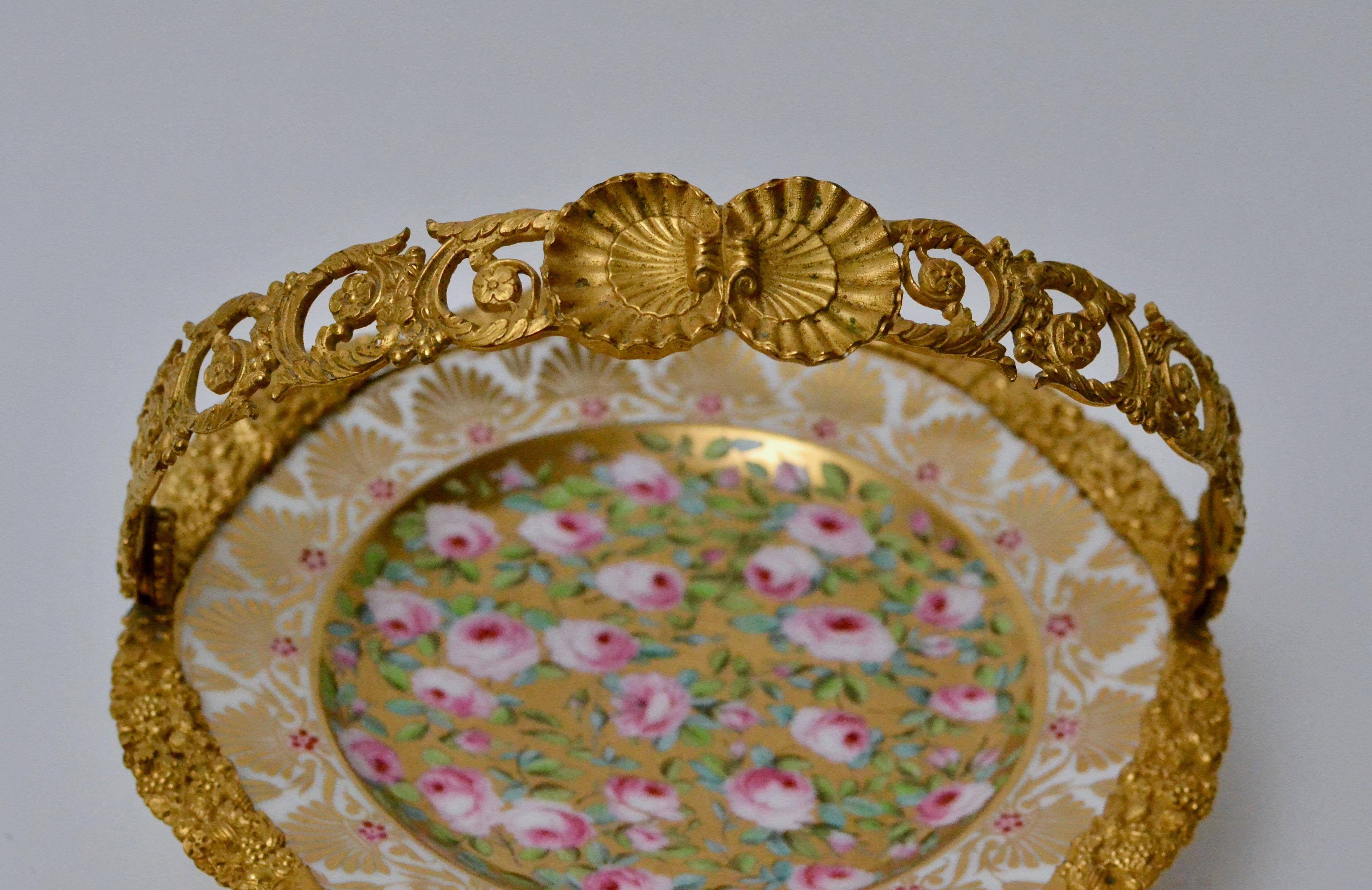 Tortenständer mit bemaltem Porzellanteller und vergoldetem Bronzegriff. Erste Hälfte des 19. Jahrhunderts. Das Porzellan ist fein mit Rosen und Gold bemalt.