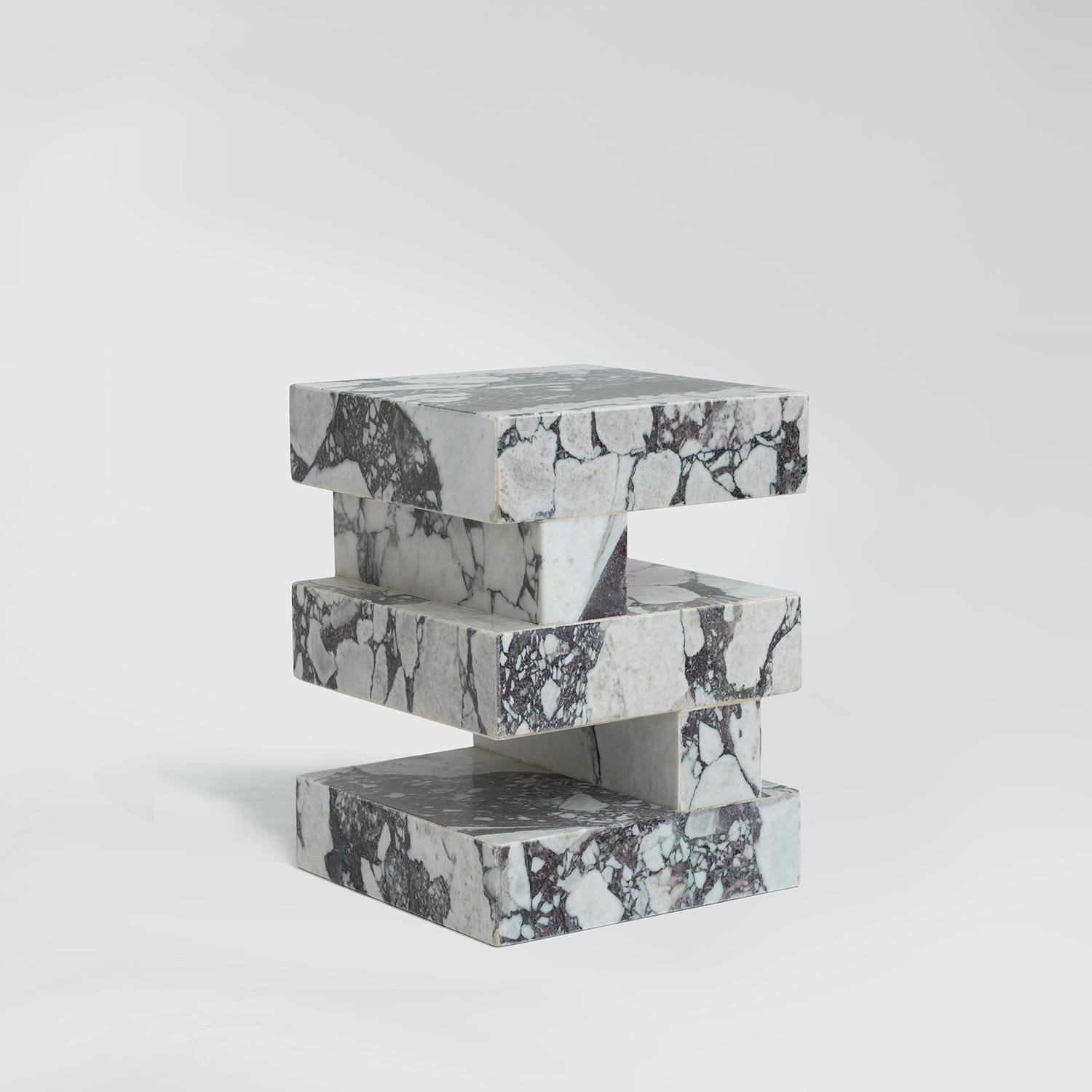 La table d'appoint SYNC est une pièce moderne et multifonctionnelle qui allie style et praticité. Fabriqué en marbre calacatta viola, sa forme en zigzag et son design en couches offrent une façon unique de poser vos livres ou d'exposer vos objets.