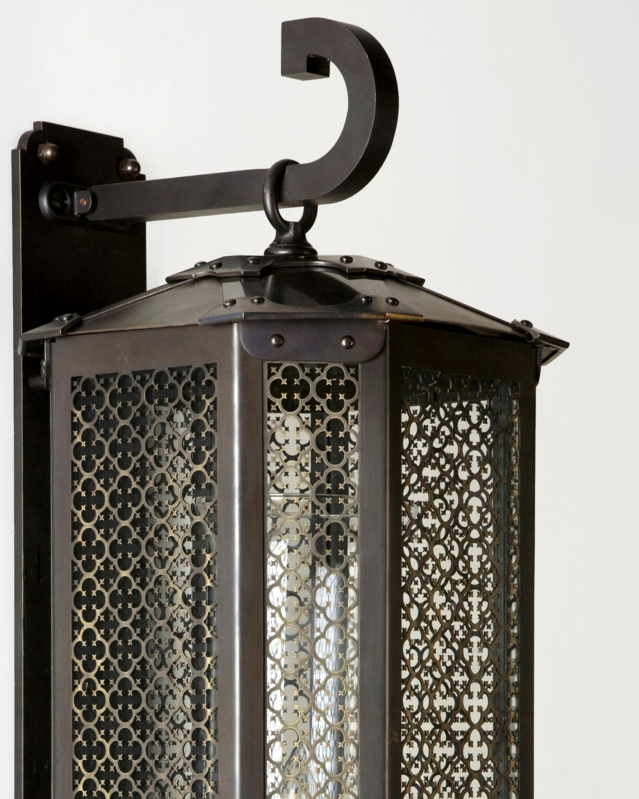 EW2432.24
The Calais Chamfered wall lantern was conceived and drawn by Designer Tracey Topping for Remains Lighting. The gossamer, lace-like scrim of fleur-de-lis and quatrefoils contrast with the muscular cast bronze studded clasps. Hanging from a