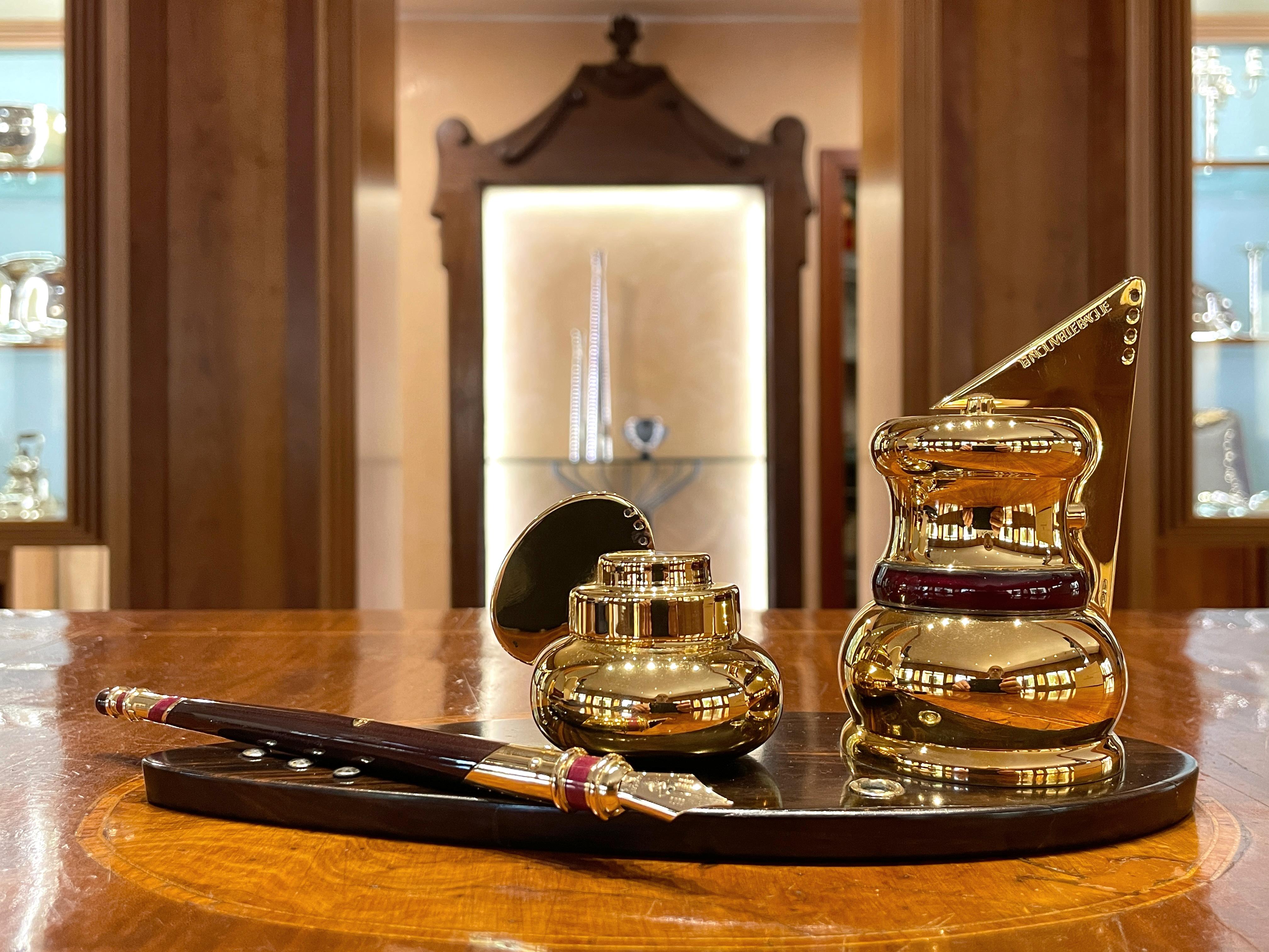 La Nouvelle Bague Metropolitan inkwell in 925/ooo yellow gold-plated sterling silver and ebony base, fire enamel details. Included is 925/ooo sterling silver, 18k gold, fire enamel and 14k gold nib. The inkwell consists of two containers, one with