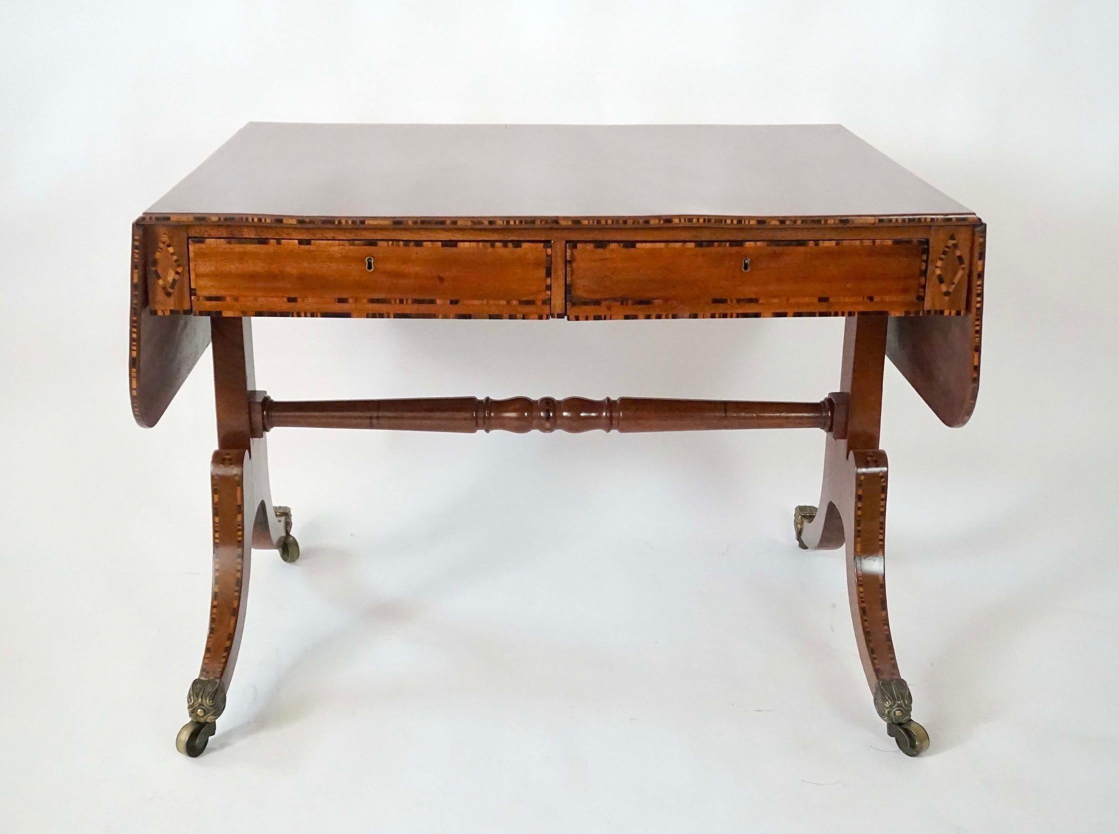 A very fine and elegant circa 1820 English regency solid mahogany drop-leaf two drawer sofa table by renowned London cabinet-maker William Wilkinson of false double-sided form having eye-dazzling calamander inlay to edges, drawer-fronts, reverse