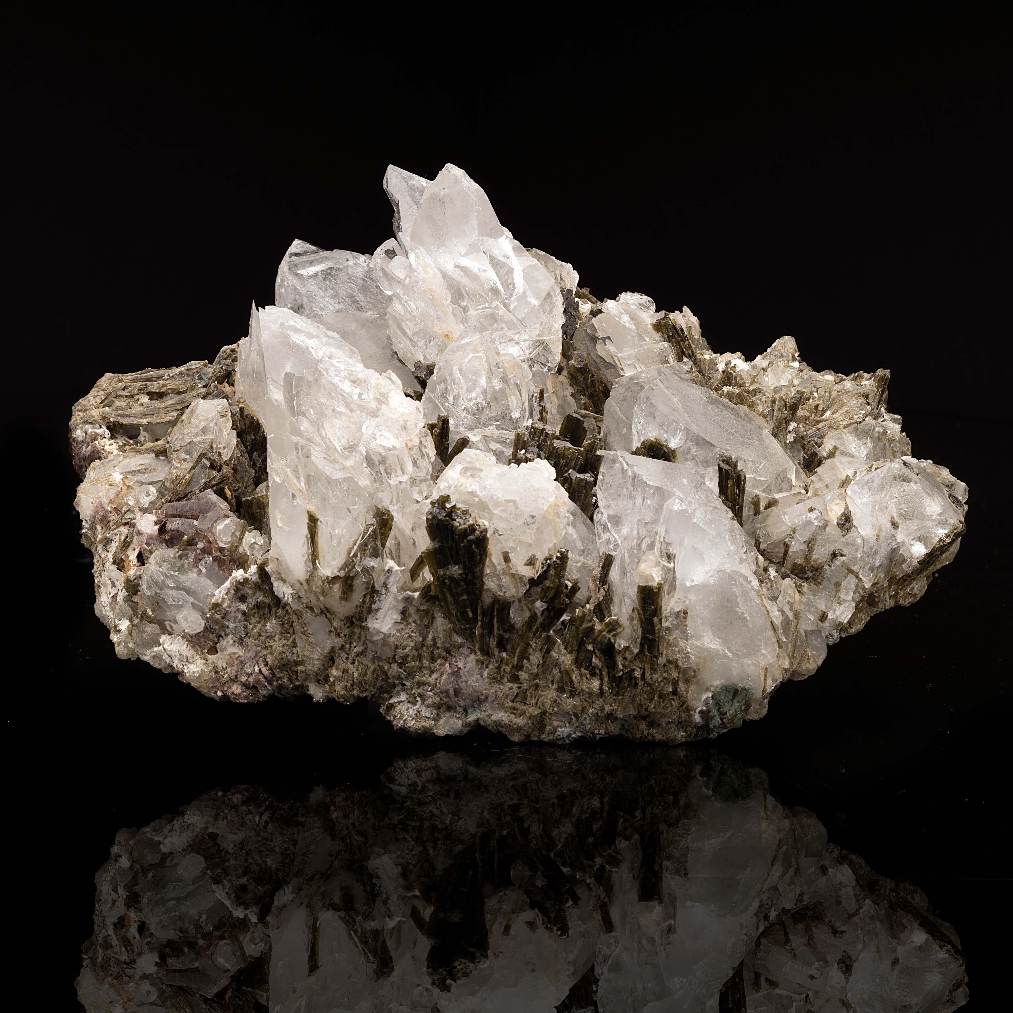 This singular formation from Pakistan features translucent calcite accented by blades of deep green epidote and purple ferroaxinite with quartz crystals on the bottom of the specimen. The lustrous calcite features rainbows. This is a substantial and