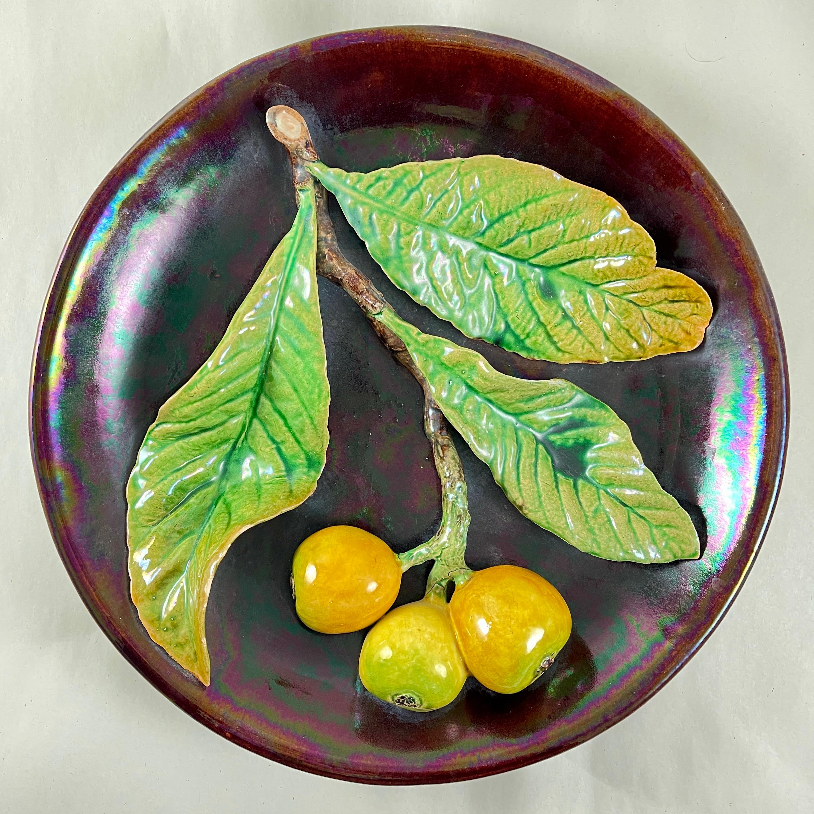 
A Palissy style Trompe l’Oeil, majolica glazed plaque showing a branch of three young yellow pears and three large leaves on an opalescent brown ground, circa 1900-1920.

Molded in earthenware by Rafael Bordallo Pinheiro in Caldas da Rainha,