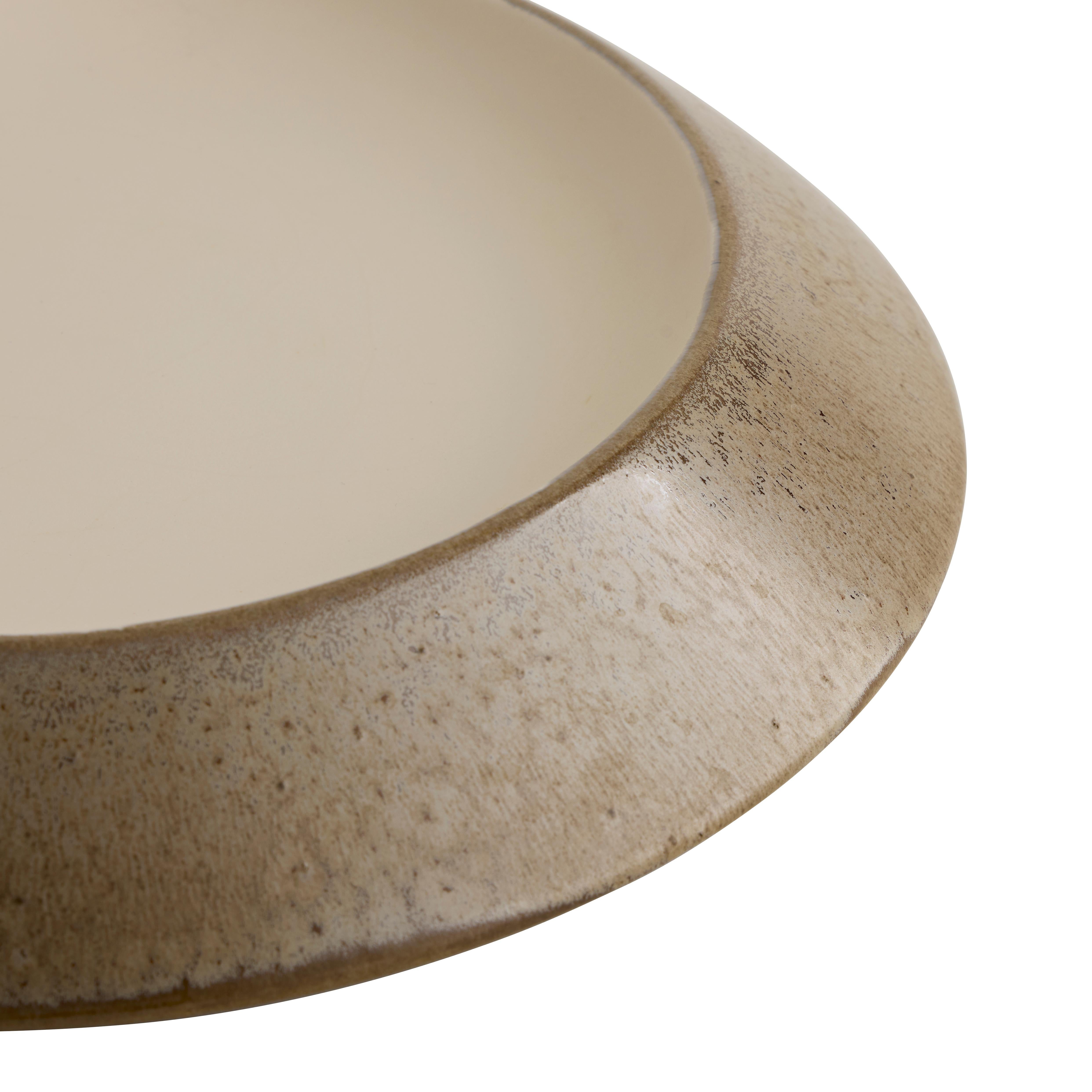 Le centre de table CALDERA a été inspiré par l'attraction de la lune, sa forme de soucoupe présentant un intérieur en ivoire mat massif. Le processus d'émaillage réactif du grès confère des variations uniques à chaque pièce, révélant le témoignage