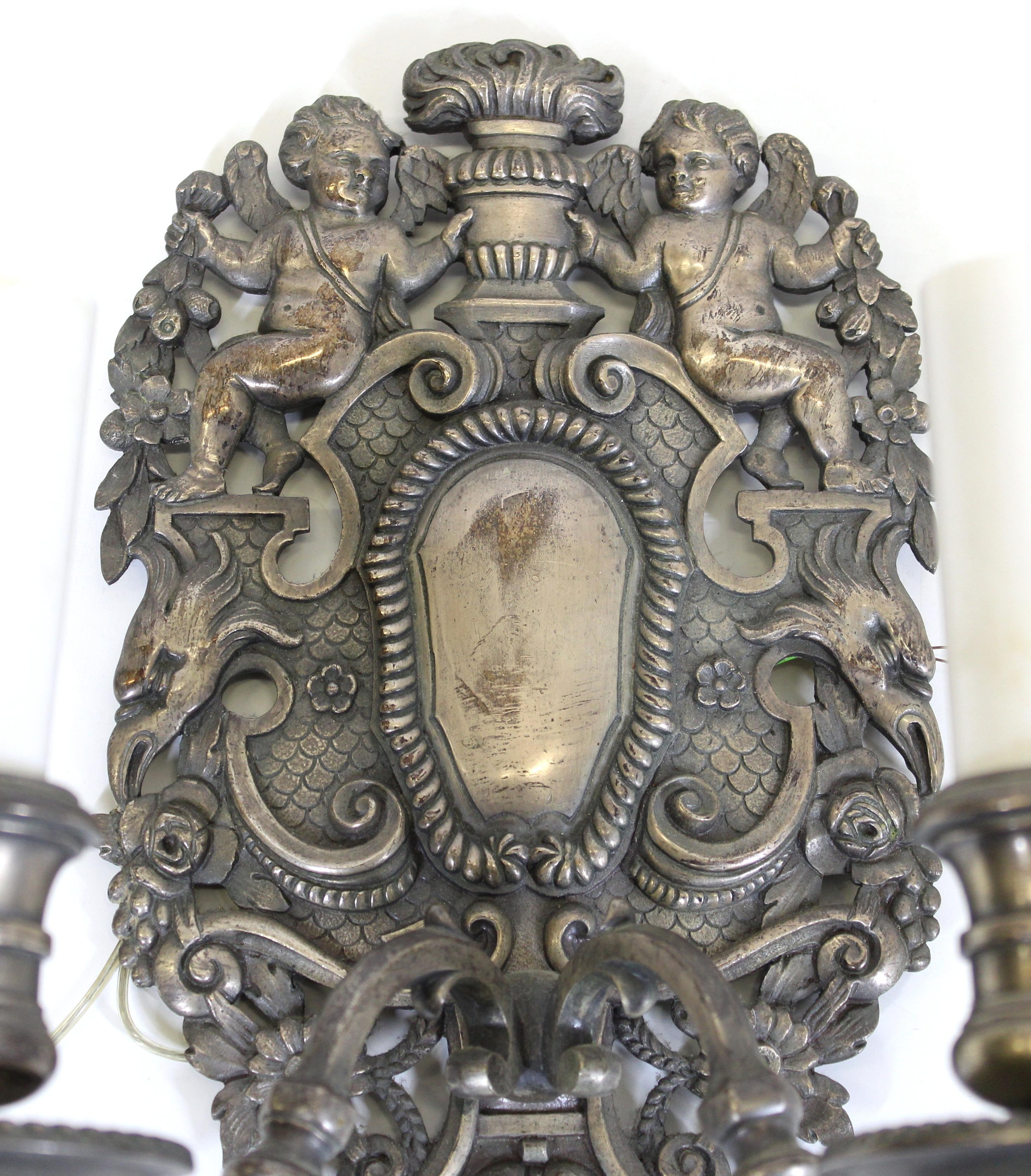 Caldwell American Renaissance Revival pair of wall sconces in silvered bronze, with ornamental cartouche back plate featuring putti. Made during the 1880's in the United States. In great antique condition with age-appropriate wear to the old silver