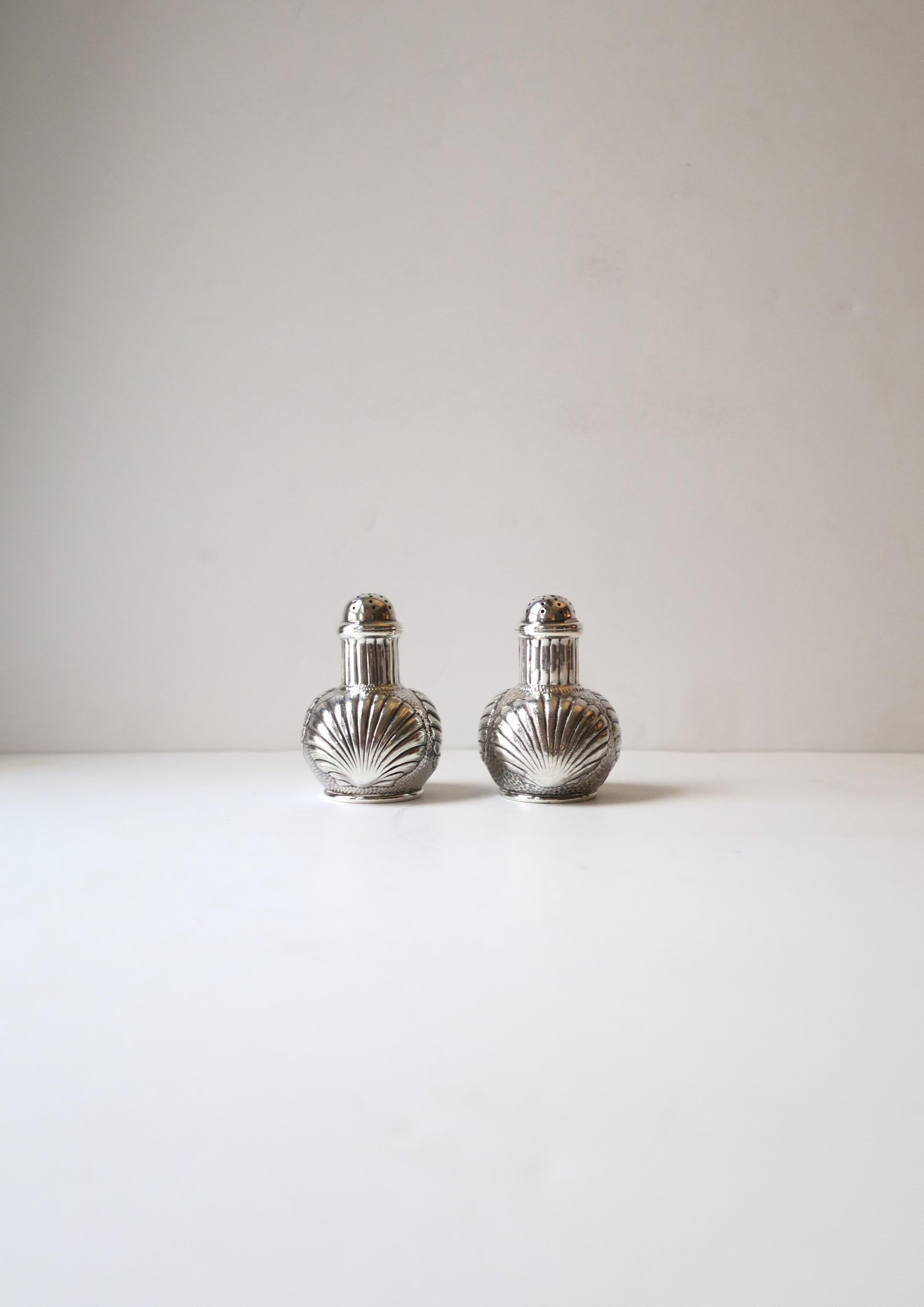 A beautiful and well-made pair of Sterling Silver salt and pepper shakers with scallop seashell design by iconic American jeweler and silversmith J.E. Caldwell & Co, circa 20th century, USA. A great set for everyday use or entertaining, indoors or