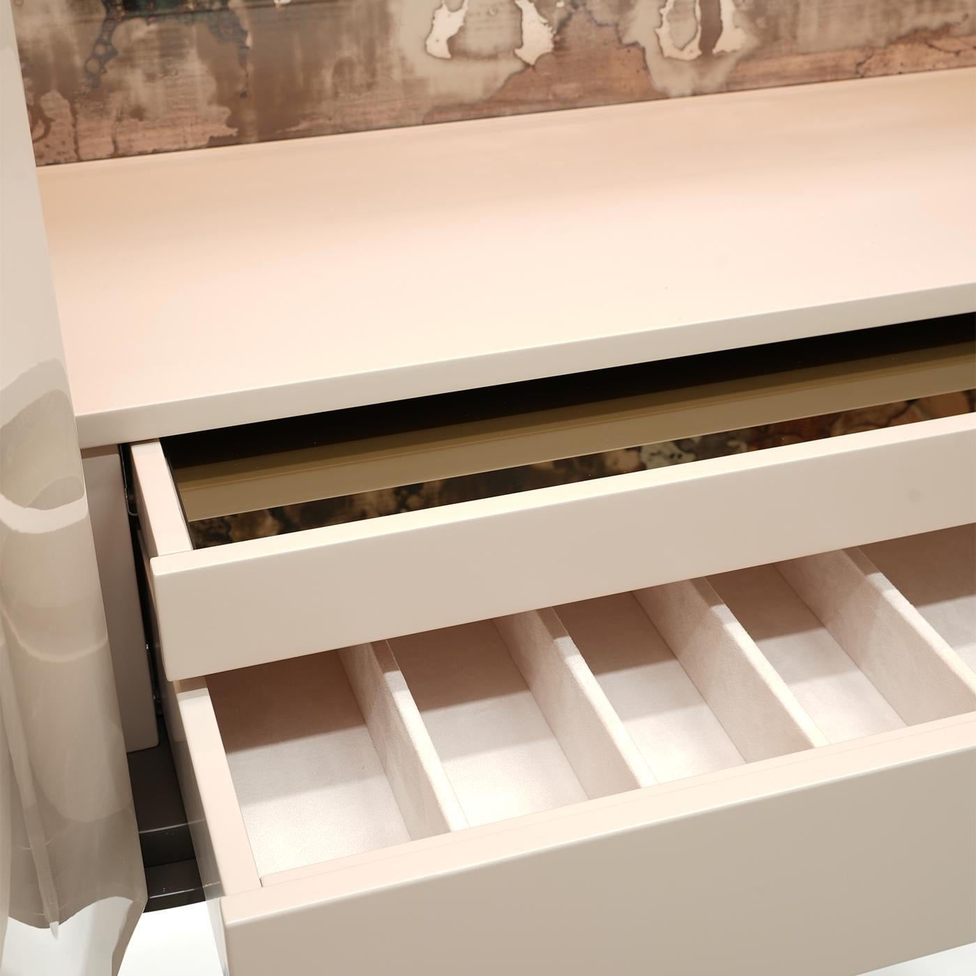 Definito da curve seducenti che ne sottolineano l'eleganza contemporanea, questo elegante mobile bar si distingue per la laccatura grigio-pietra che decora le ante con un raffinato effetto sfumato. Dettagli metallici bronzati spazzolati
