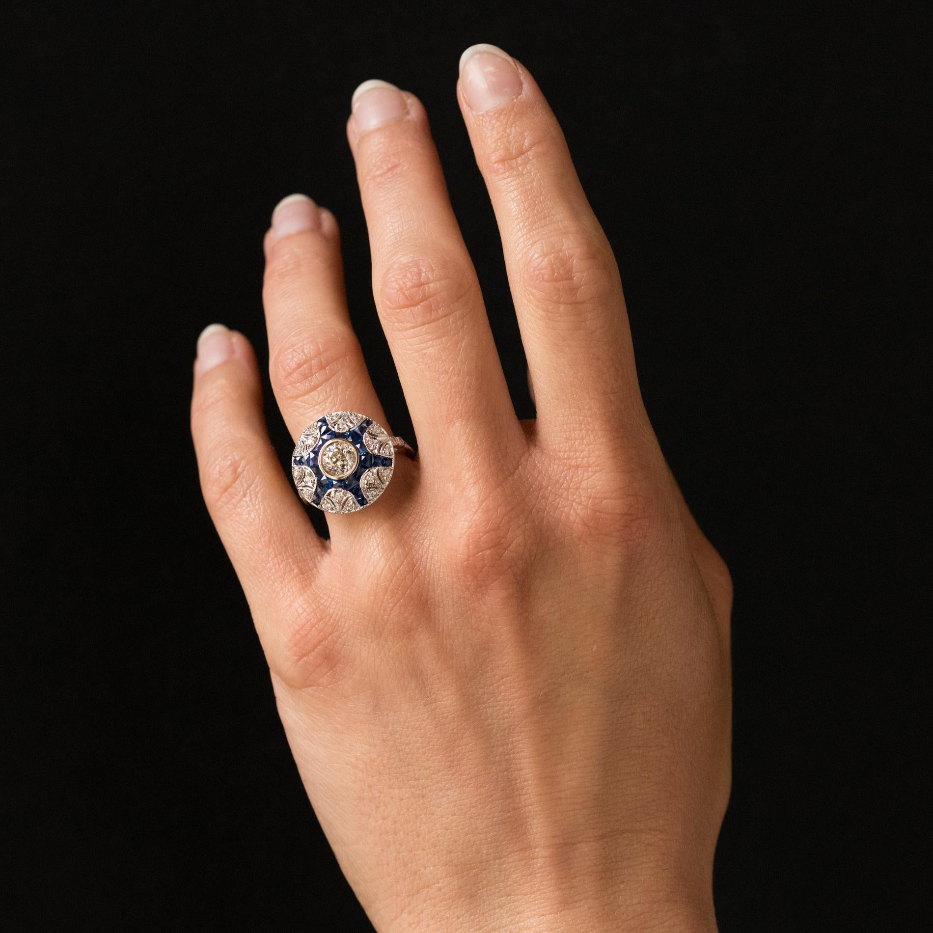 Ring in 18 karats white gold.
Magnificent round shape ring, it is closed set in its center of a brilliant- cut diamond, on a starry openwork decor which is set with calibrated sapphires and brilliant- cut diamonds. The start of the ring is set on