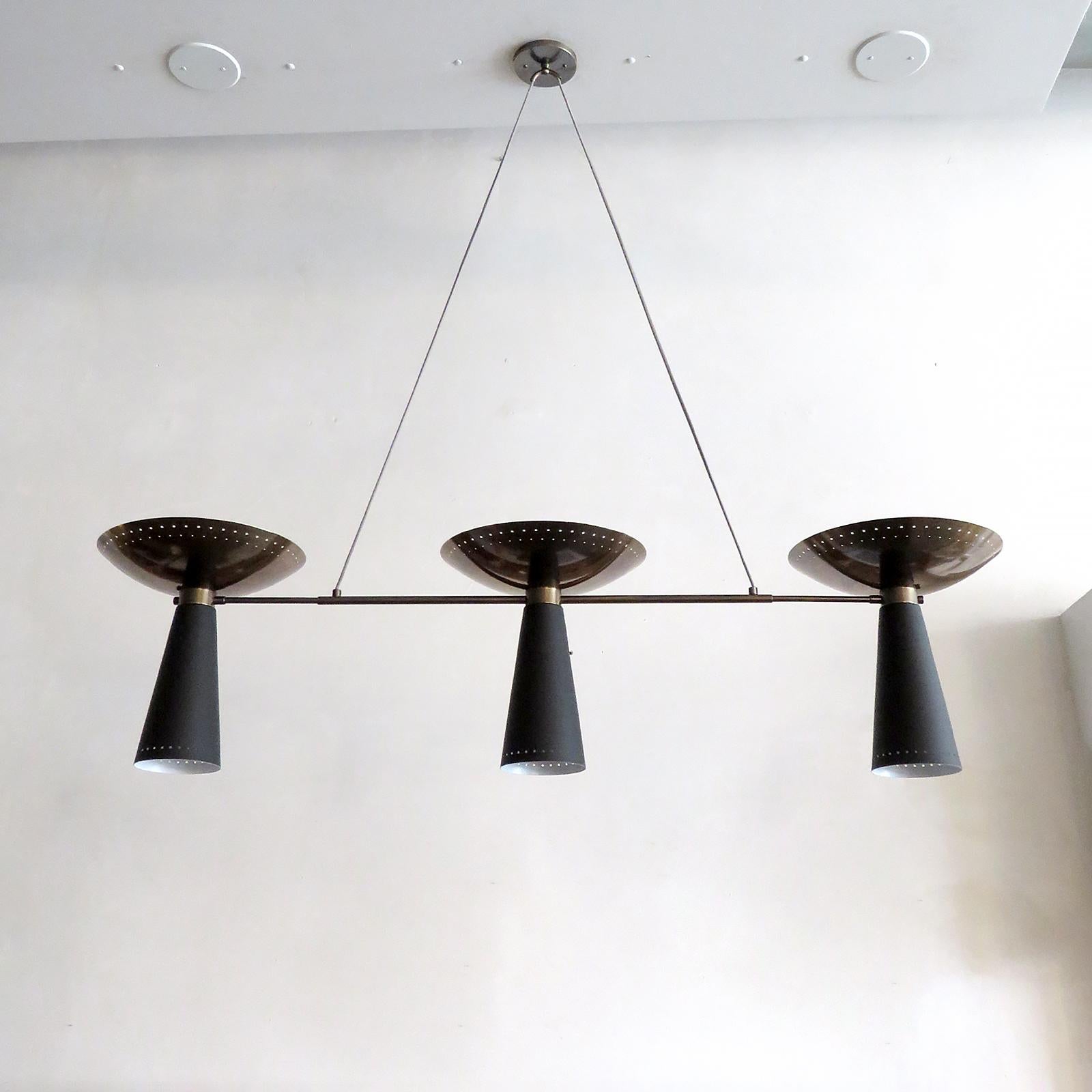Splendido lampadario Calice-3 progettato da Gallery L7, realizzato e rifinito a mano a Los Angeles in ottone americano, con una fila di tre up-lights in ottone invecchiato e down-lights smaltati di nero. Perforazioni lungo i bordi del cono, sospese